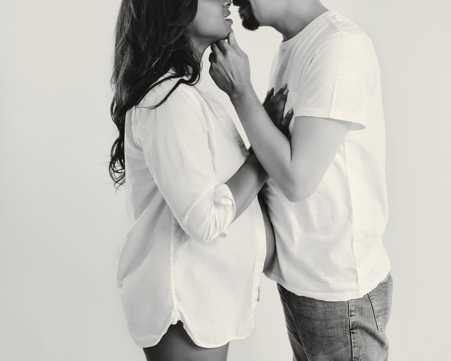 Intimate black and white photo of a romantic couple in white clothing about to kiss.