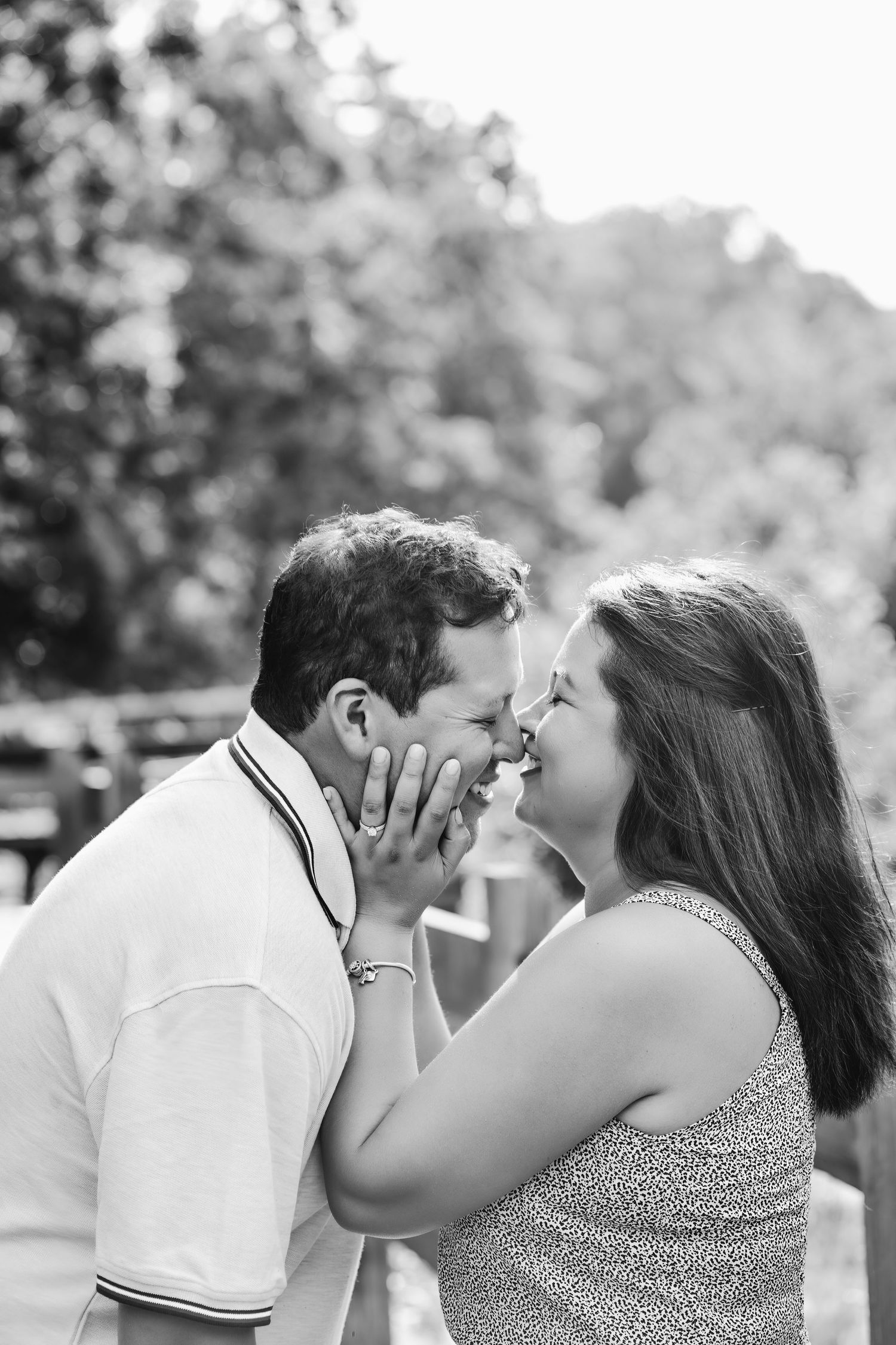 A couple in white and patterned clothing share a tender kiss in a black and white photo series outdoors.