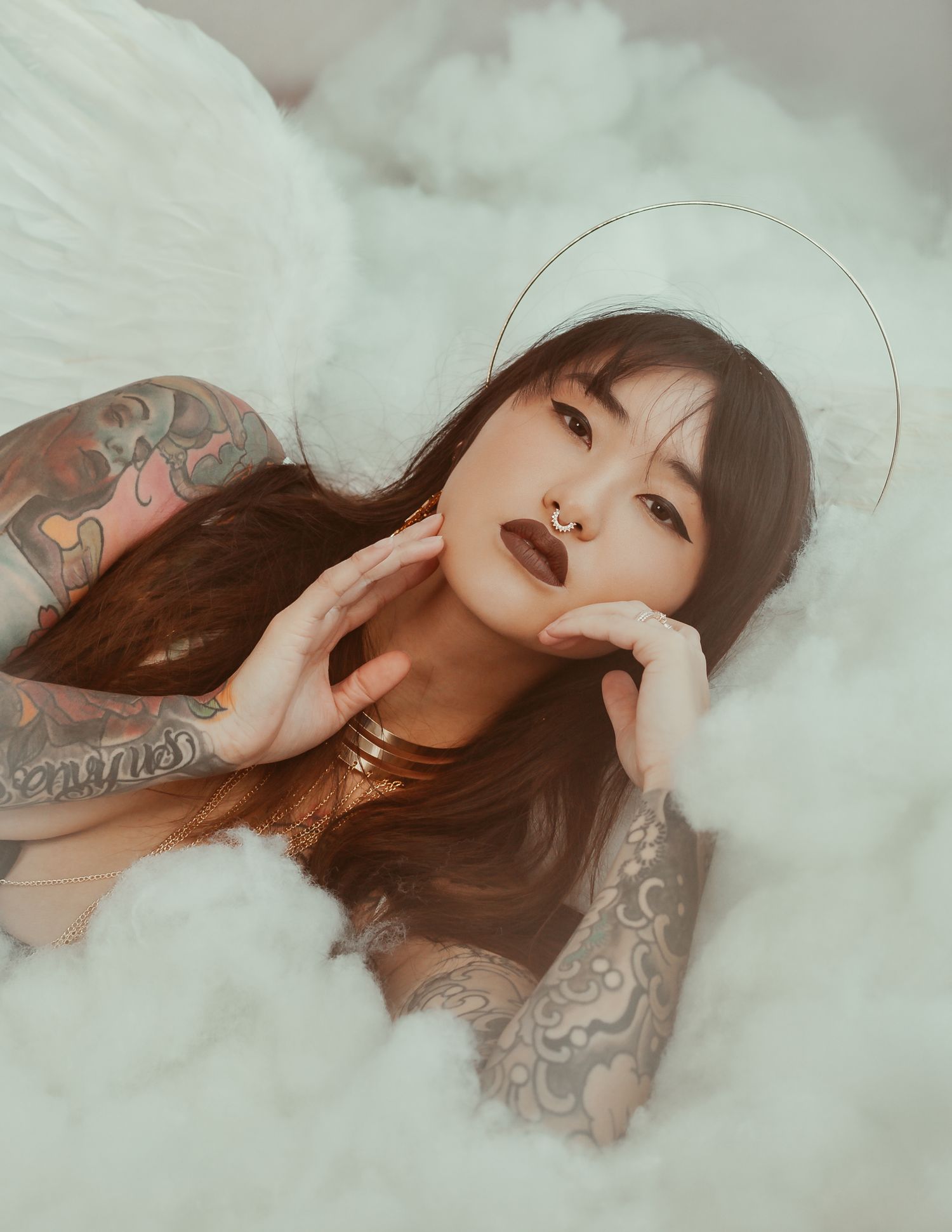 Dreamy portrait series showing a woman in soft lighting lying on white fabric with ethereal poses and dramatic makeup.