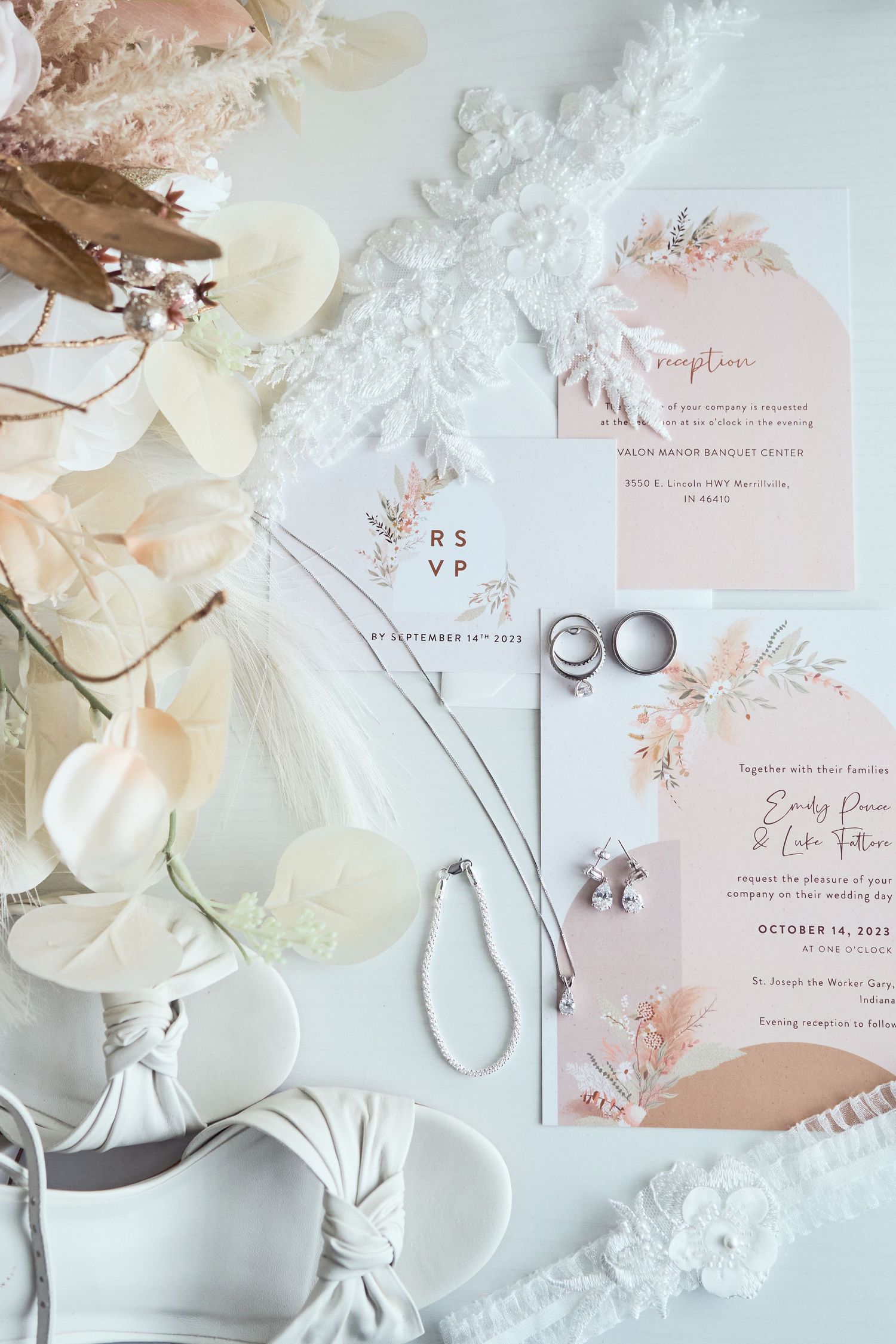 Elegant wedding stationery suite with blush pink florals, white flowers, and silver rings on a light background.
