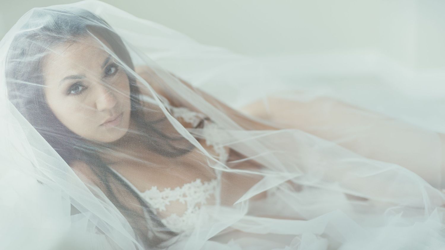 Dreamy boudoir photography featuring soft tulle veil and romantic lighting.