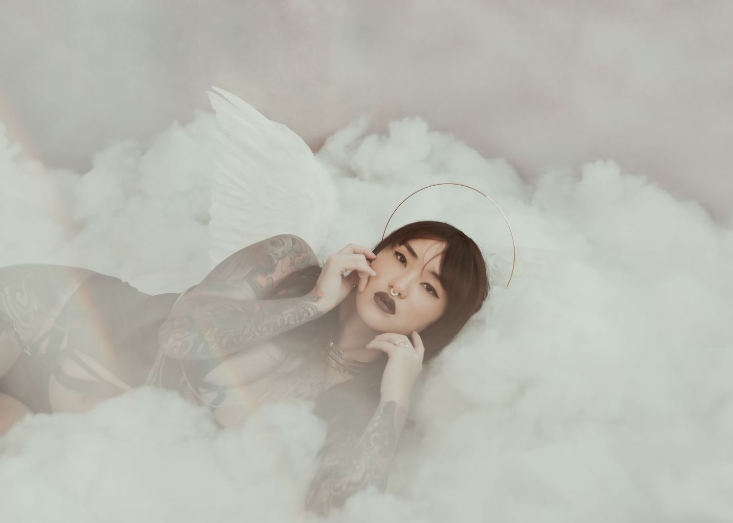 Dreamy monochromatic portrait in soft cloudy setting with ethereal lighting effects.