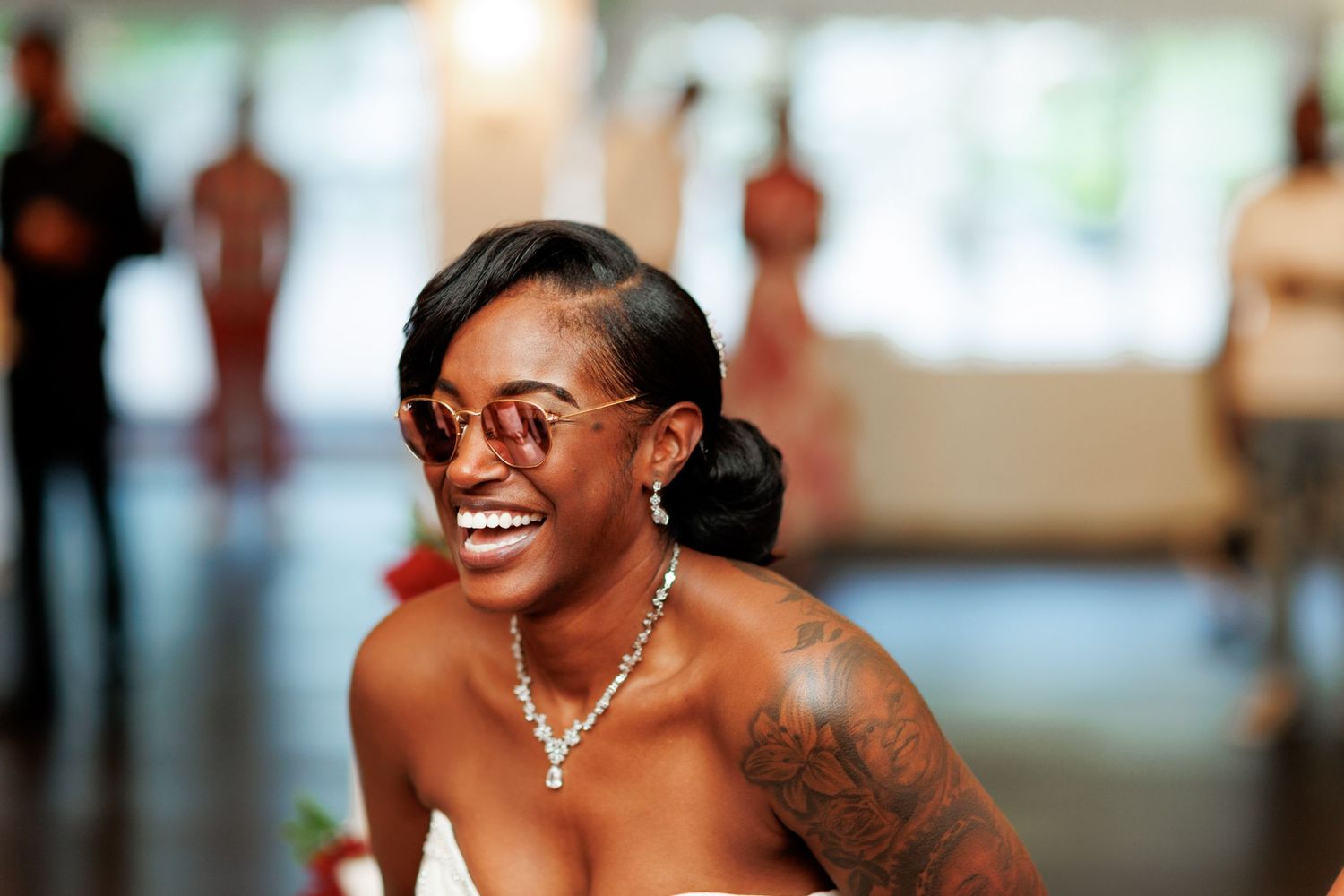 Guest at wedding reception wearing elegant jewelry and strapless dress smiles radiantly.