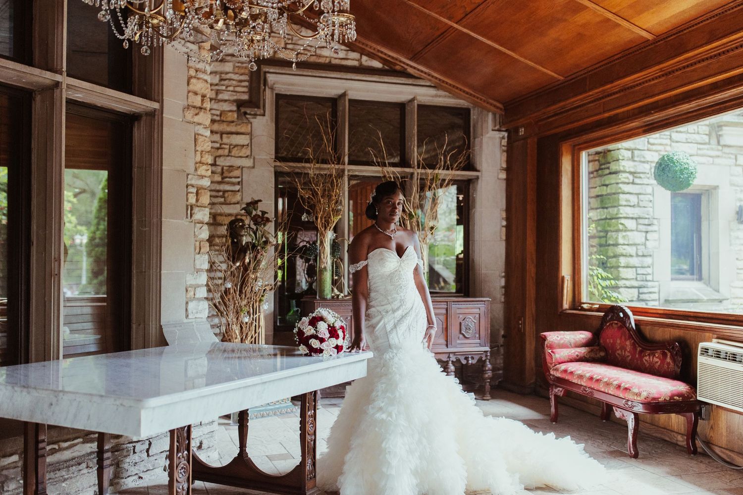 Wedding venue interior featuring stone walls, rustic wooden ceiling, and elegant table setting.