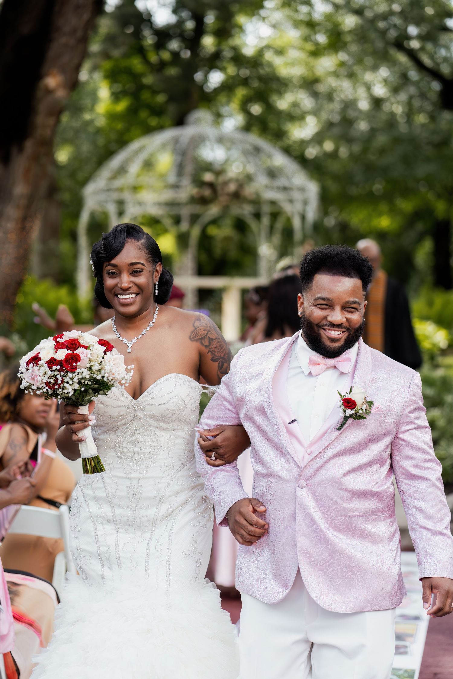 Happy newlyweds walking down the aisle at outdoor garden wedding ceremony.