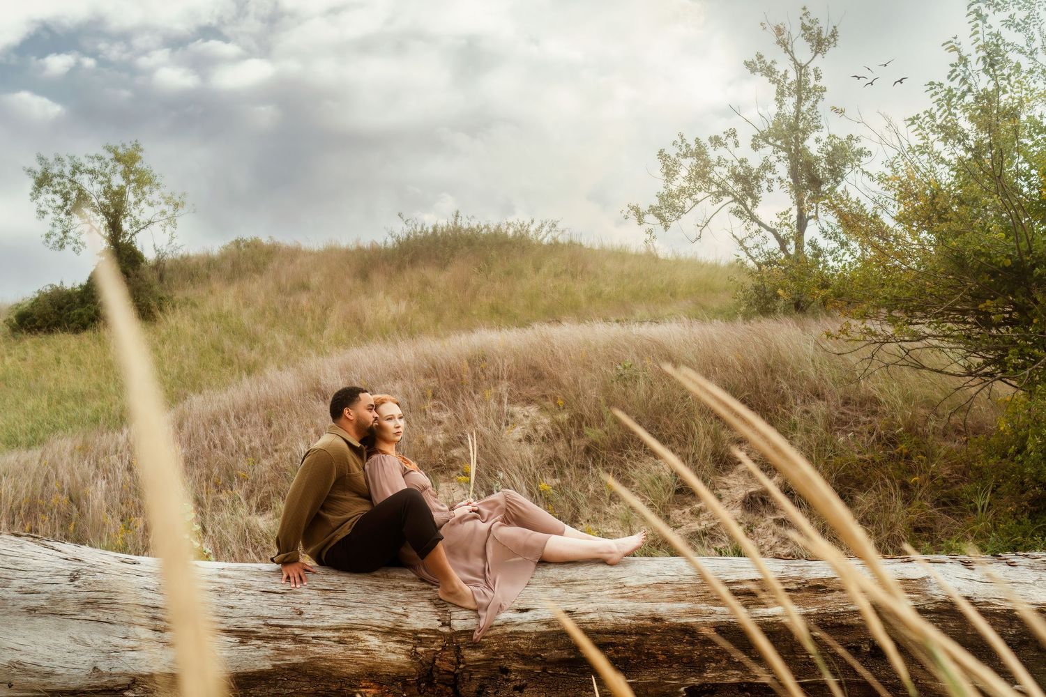 A couple lying in a meadow enjoying a romantic moment together in golden sunlight.