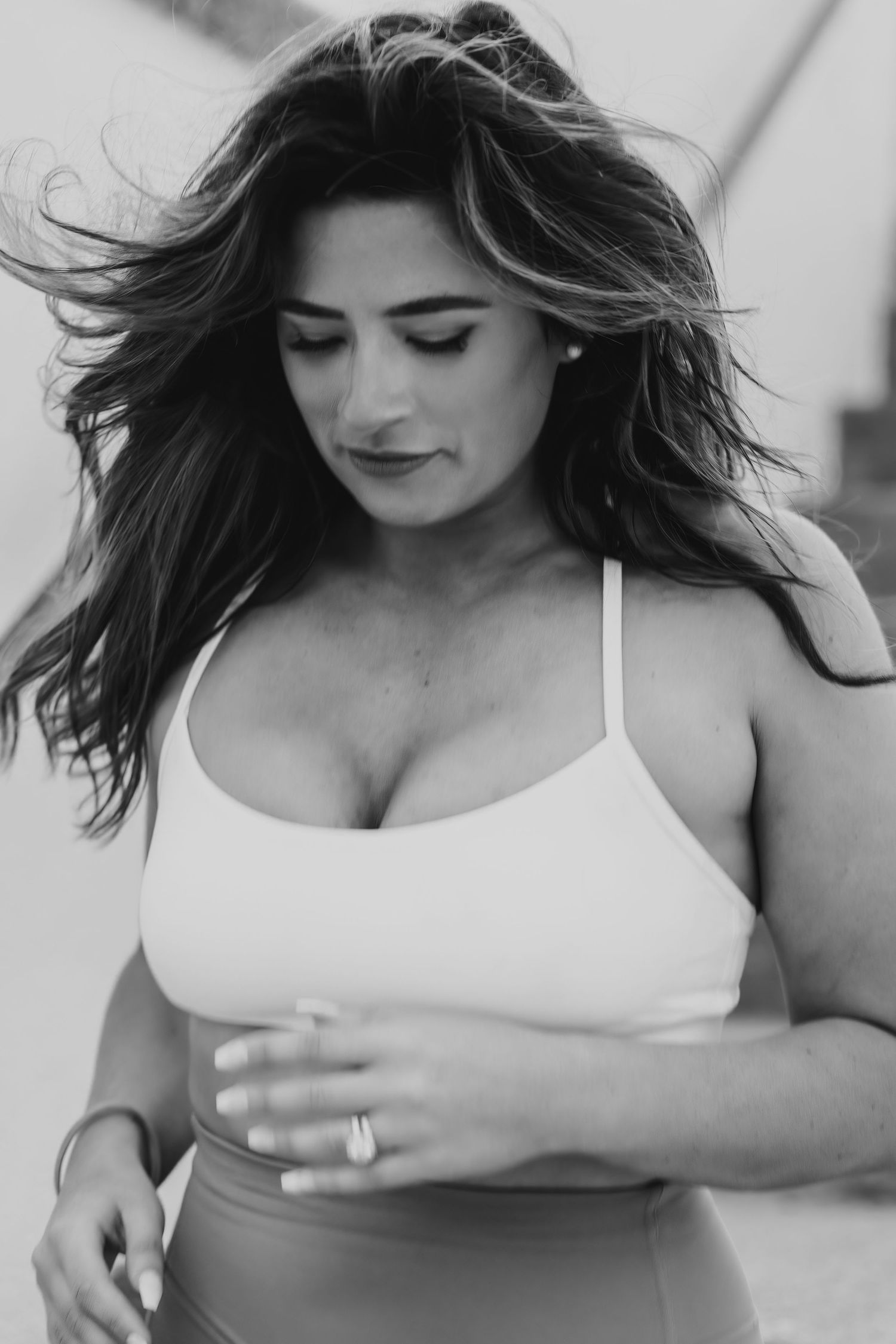 Black and white portrait of woman in athletic wear with windswept hair.