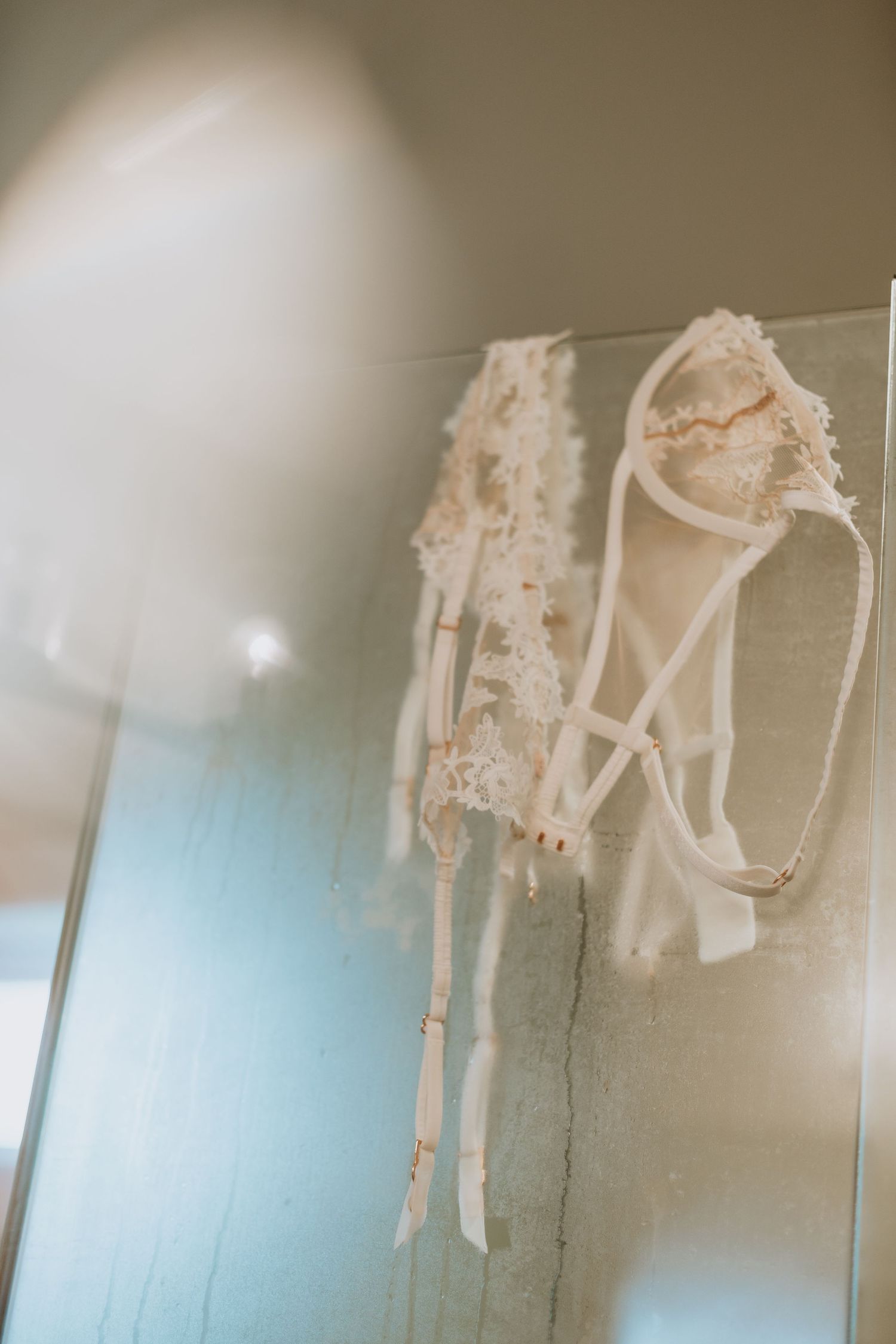 A delicate white lace wedding dress and sheer veil hanging on display.