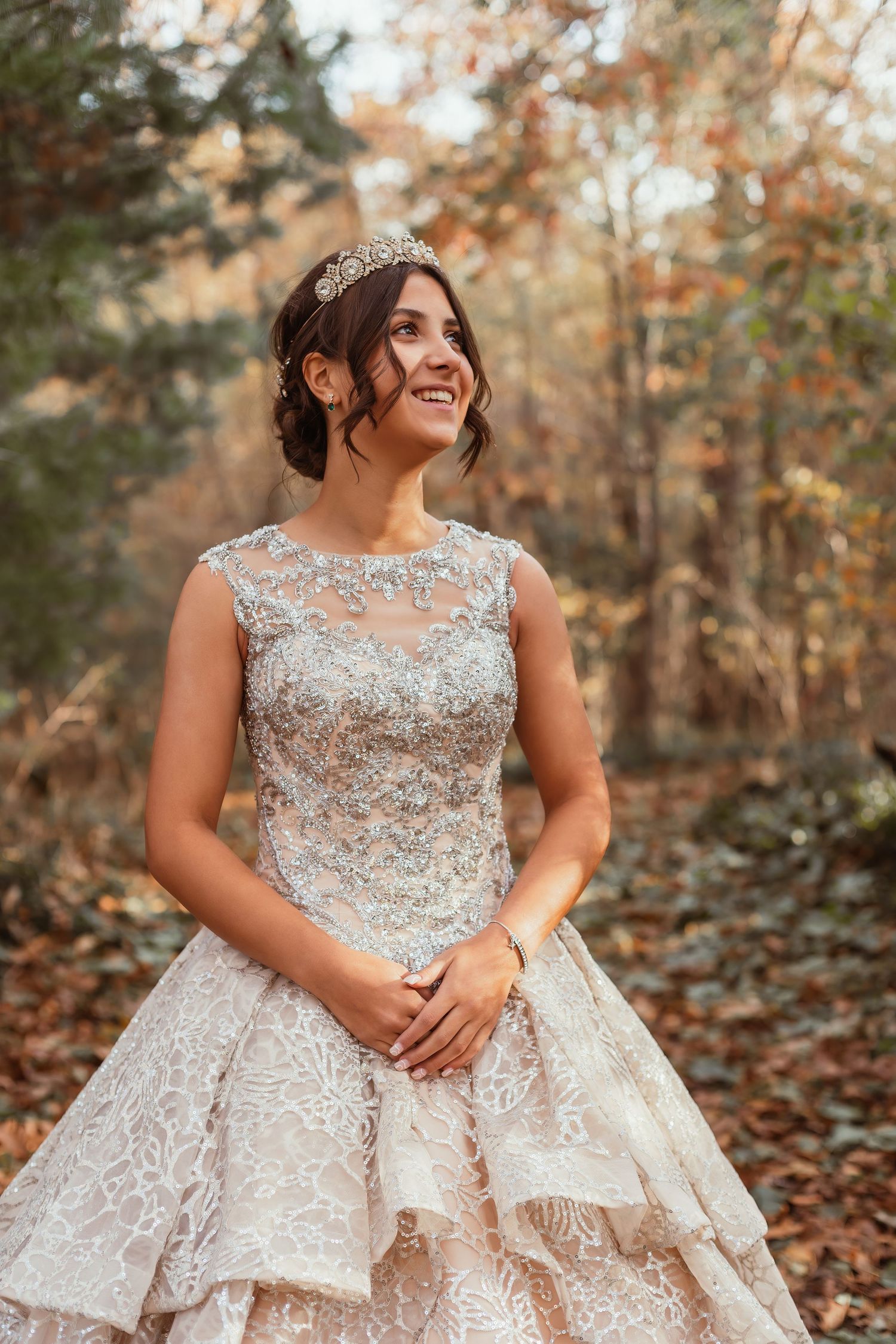Stunning bridal portrait featuring a beaded ball gown and crystal tiara in an autumn forest setting.