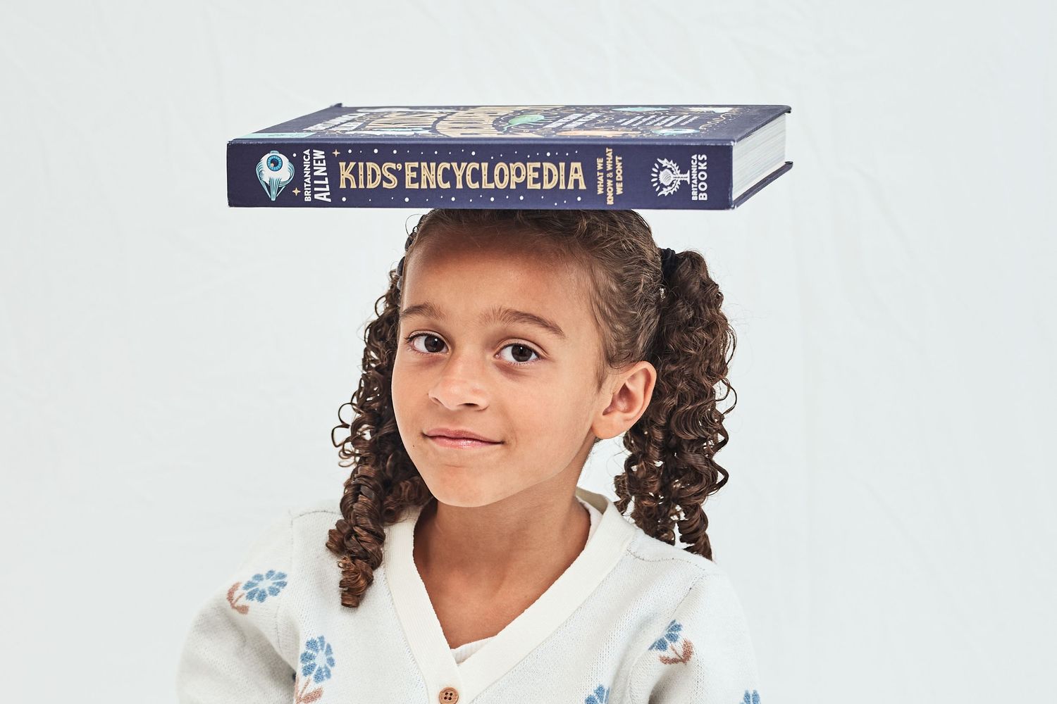 Two images of a 'Kids Encyclopedia' book positioned at different angles against a white background.