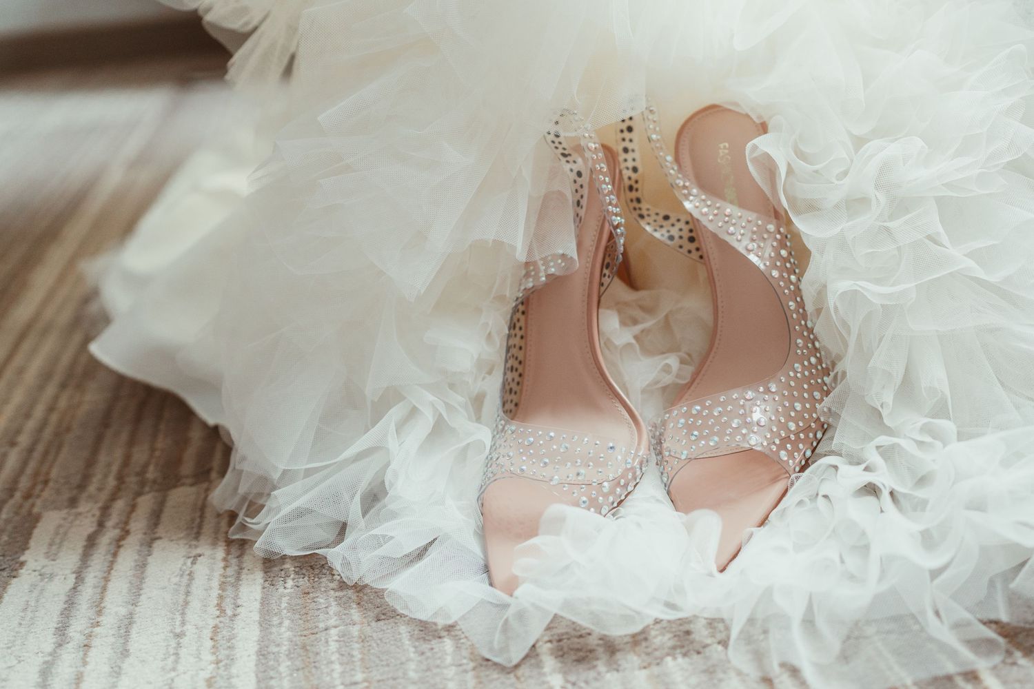 Sparkly rhinestone-encrusted wedding heels nestled in white tulle fabric.
