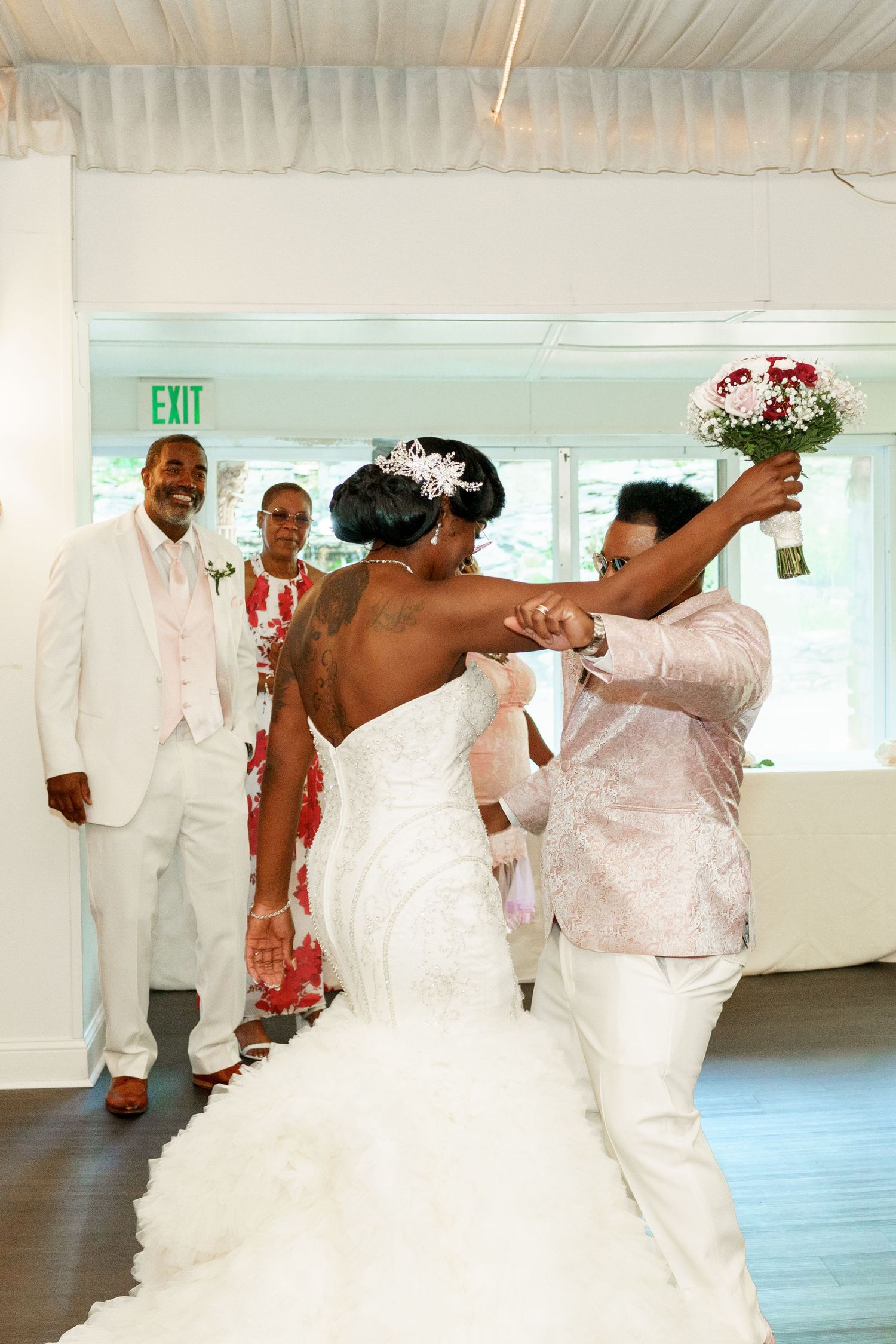 A lively dance celebration with the wedding couple surrounded by guests in white attire.