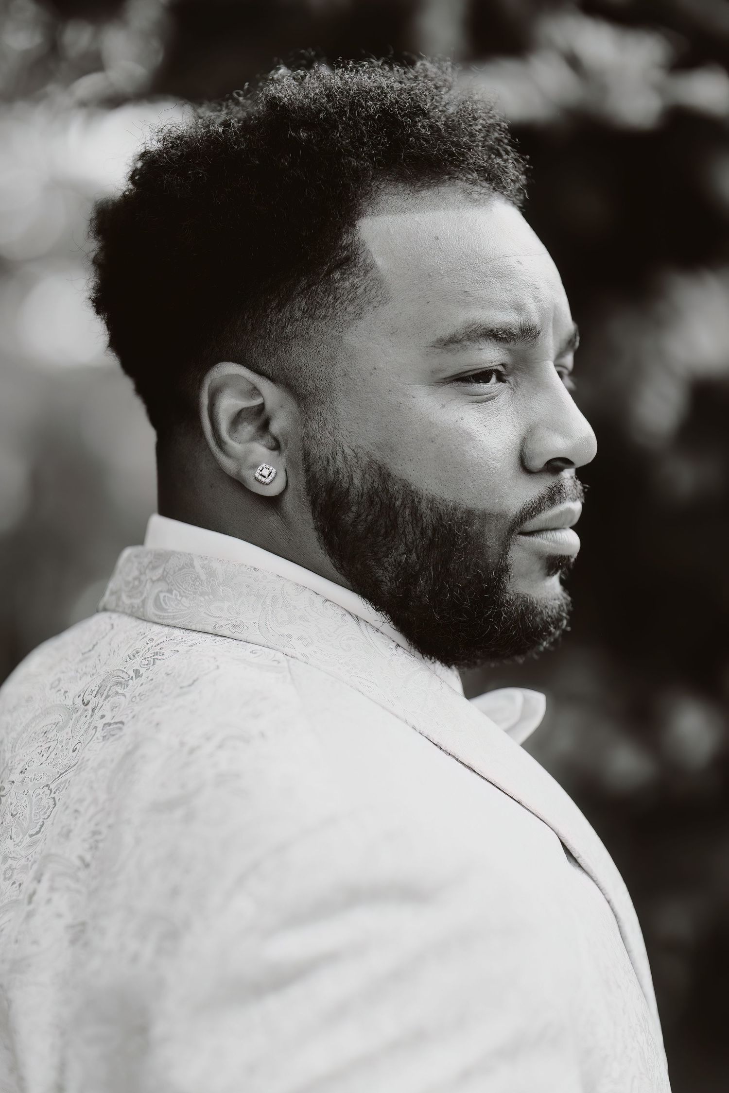 Black and white profile portrait of person in textured formal jacket.