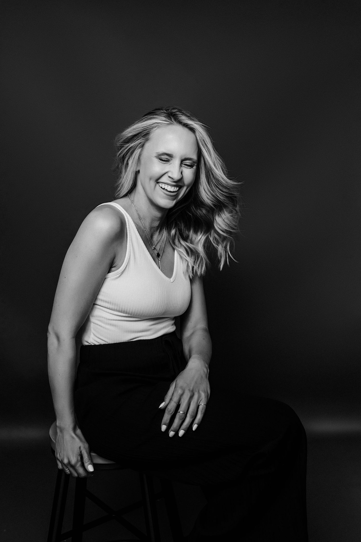 Black and white photo sequence of a person in a white tank top and dark pants moving dynamically against dark background.