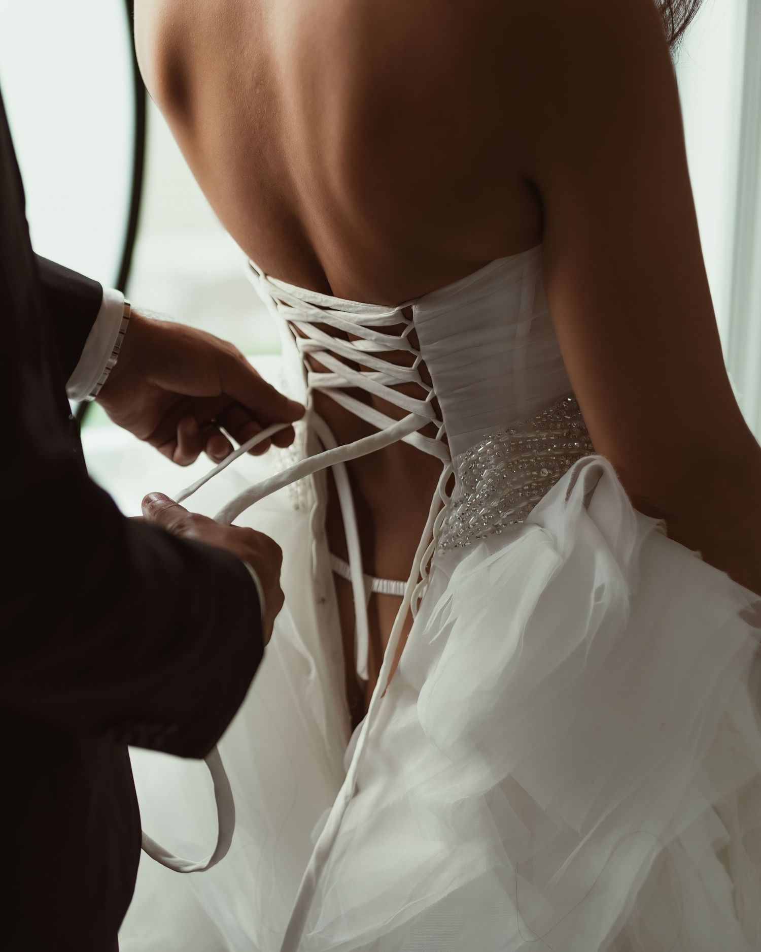 Elegant corset detail of white wedding gown being fastened.