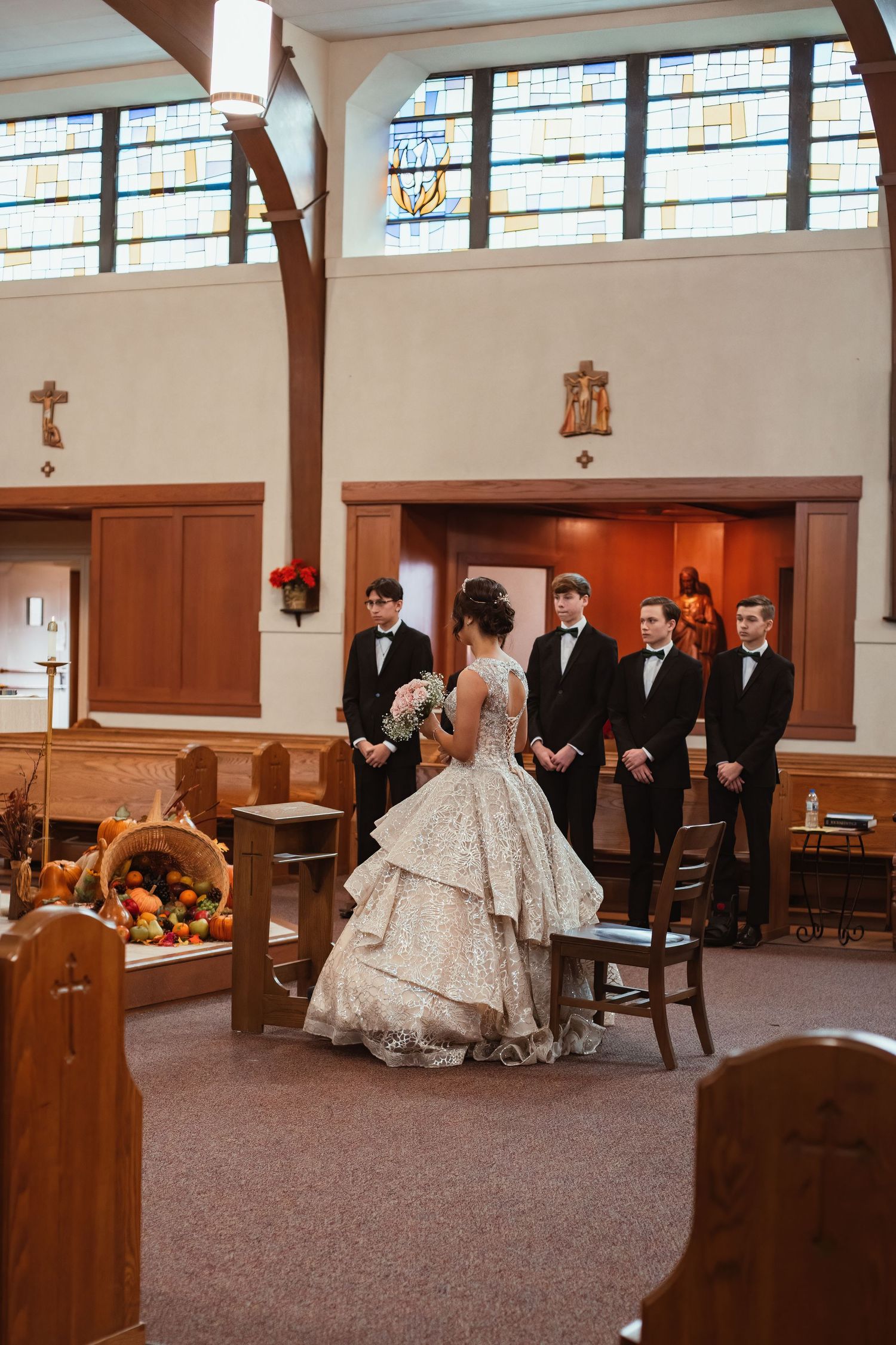 An elegant wedding ceremony in progress inside a church with stained glass windows and wooden pews.