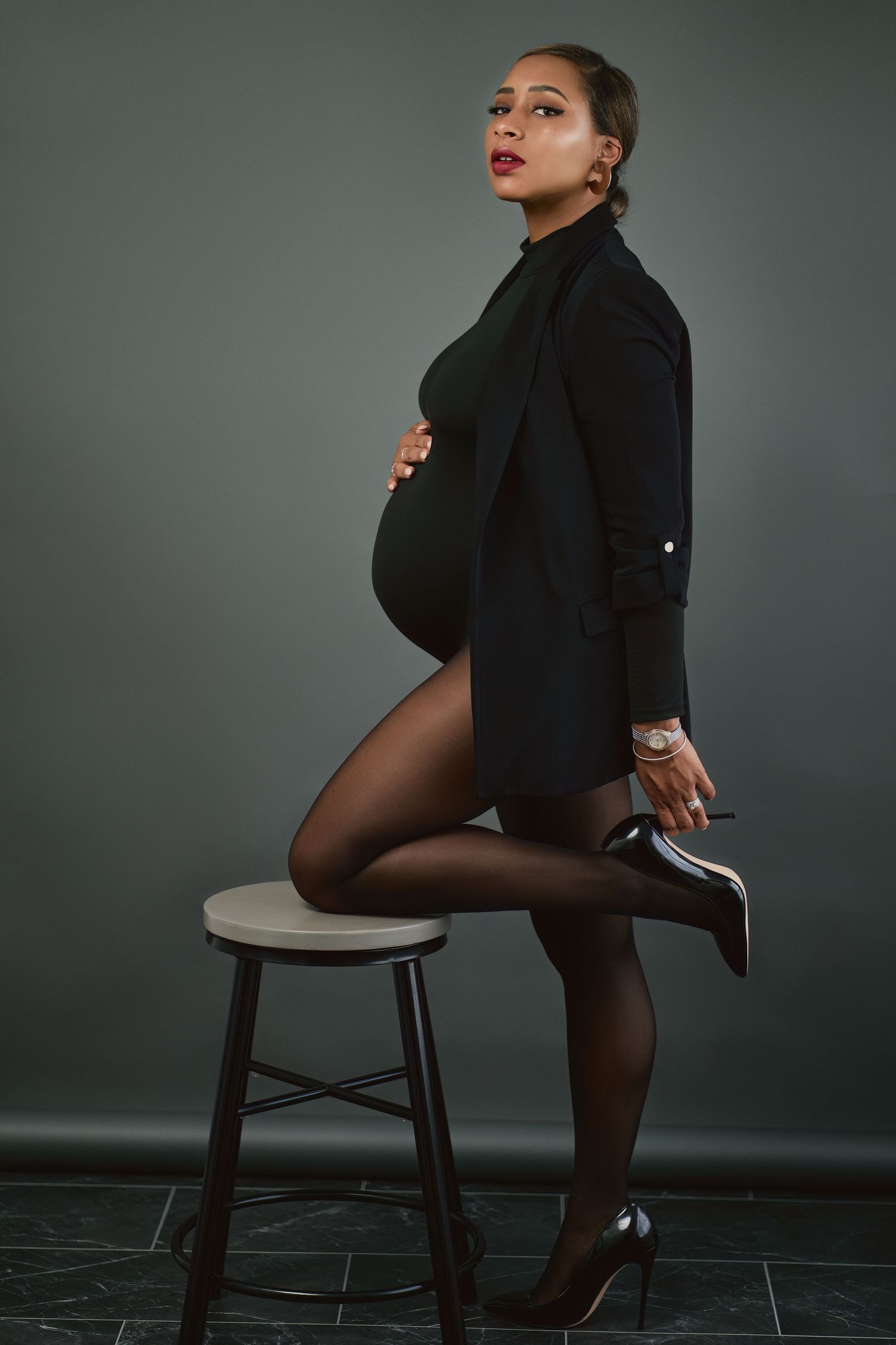 A series of dramatic fashion poses on a black chair against a dark backdrop showcasing elegant black attire.