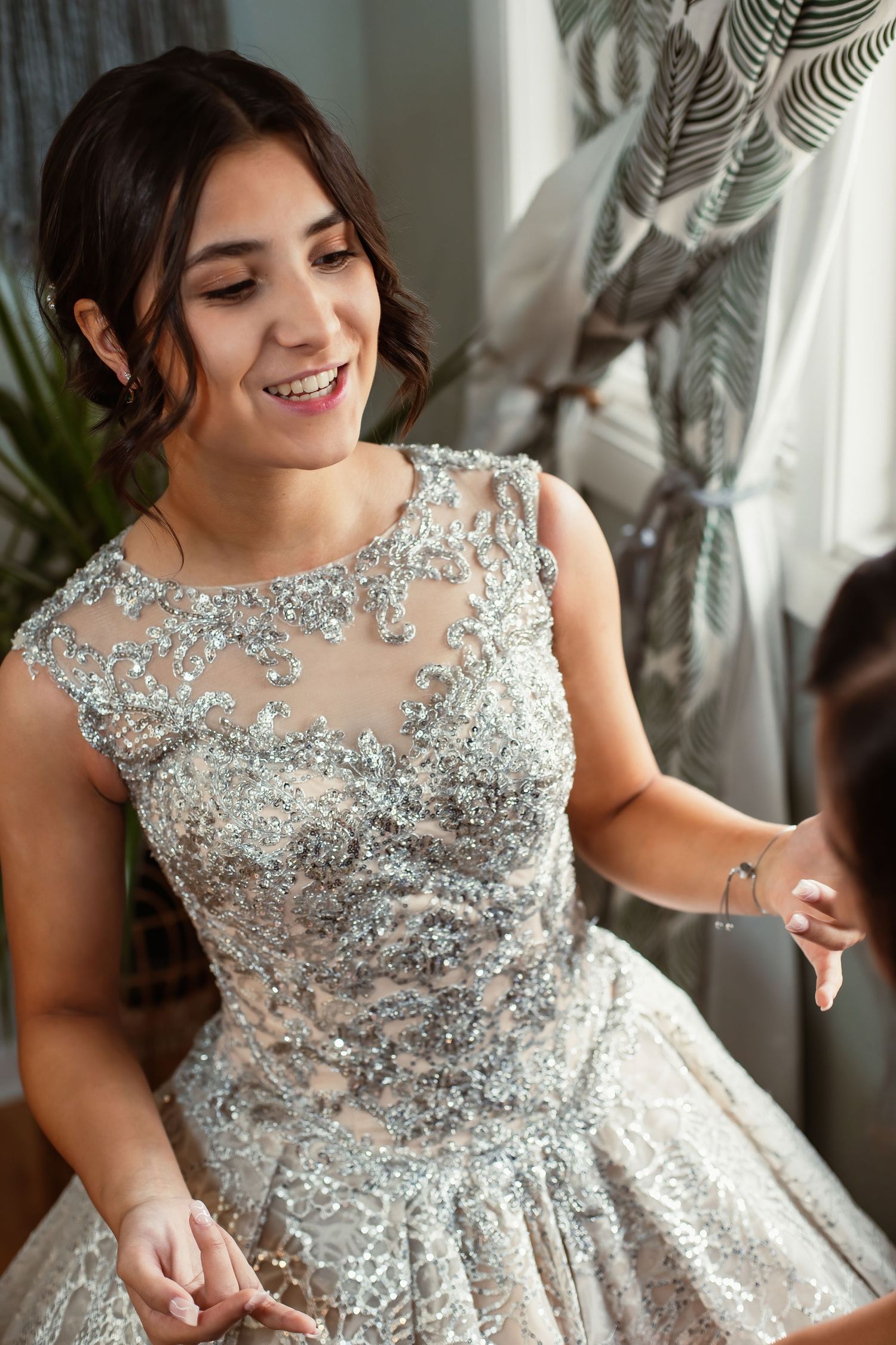 A stunning beaded wedding dress sparkles in natural light during preparations.