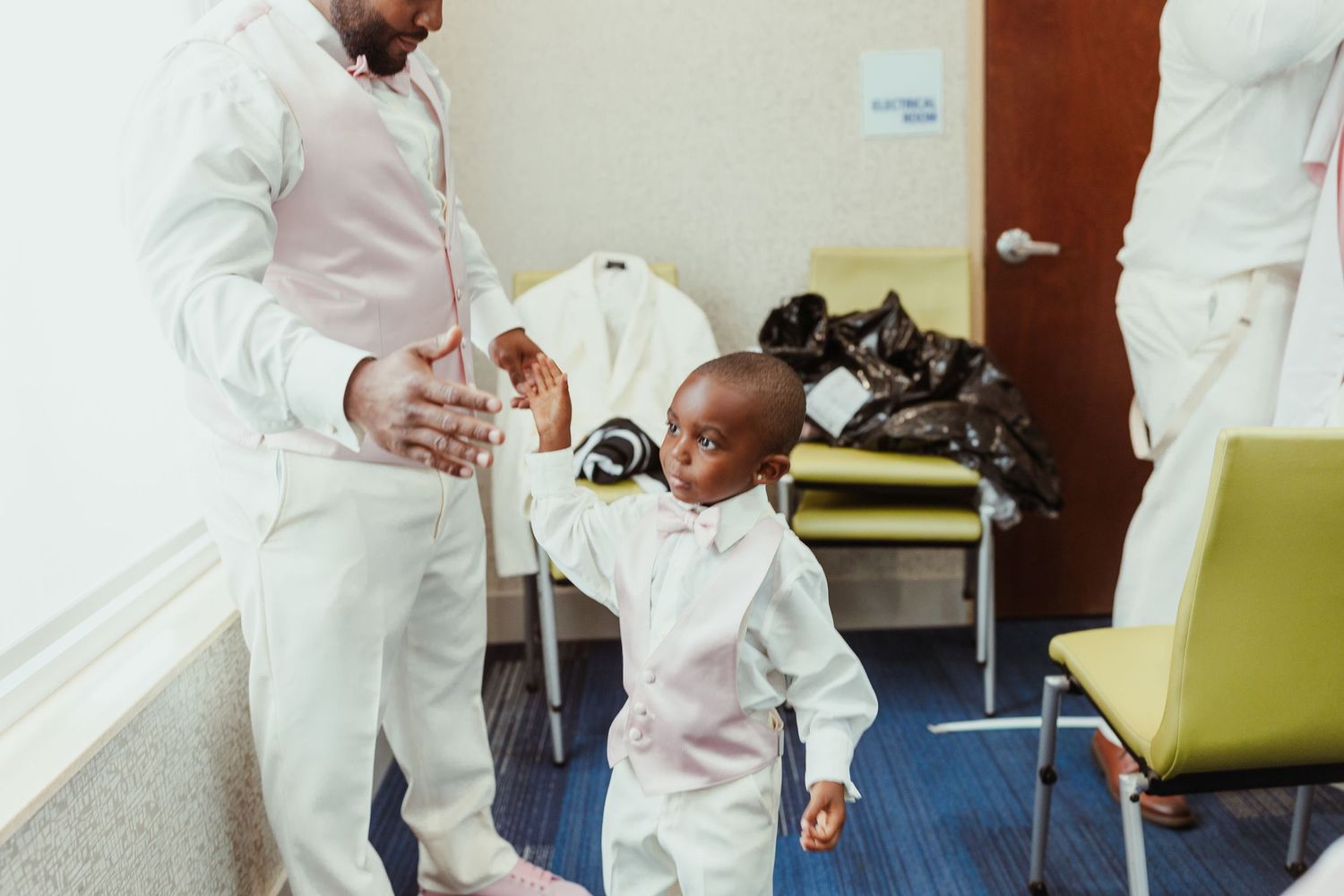 A sweet moment showing a tiny tot in matching white attire with an adult during what appears to be a formal occasion.