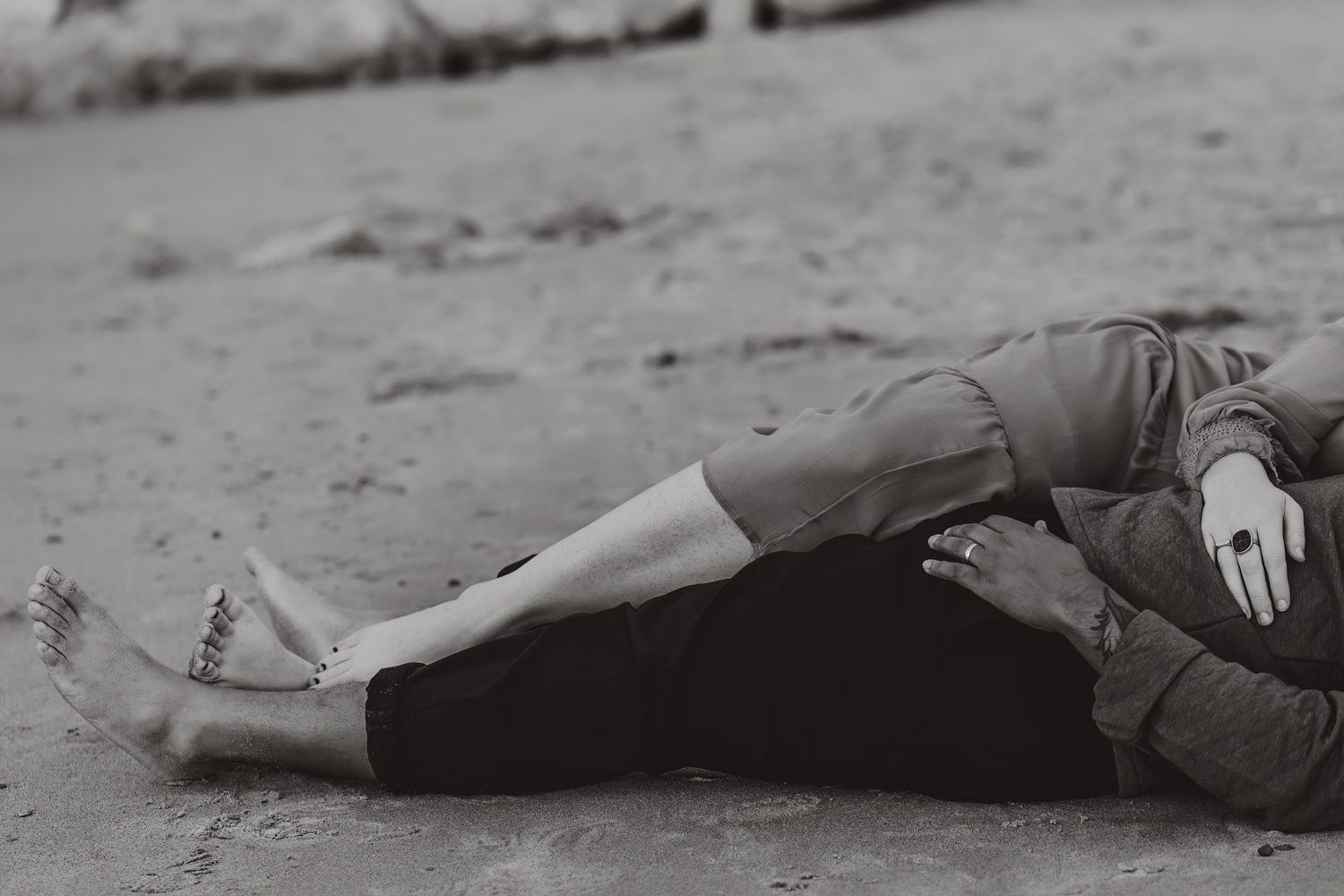 Black and white artistic portrait of couple relaxing on beach.