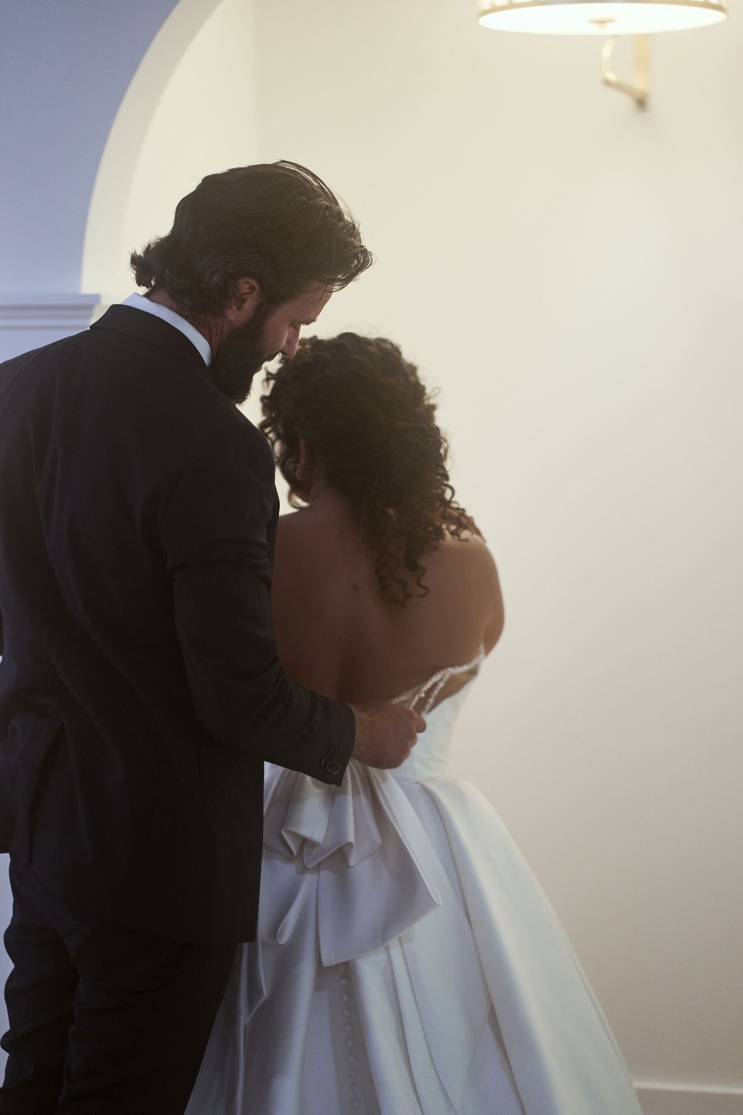 Wedding couple shares an intimate moment during their first look in a softly lit indoor setting.