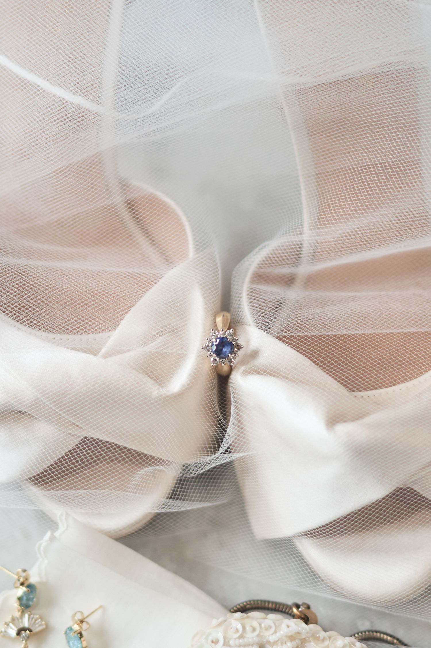 Delicate white tulle fabric and satin bows with sparkling jeweled accents create an elegant bridal accessory display.