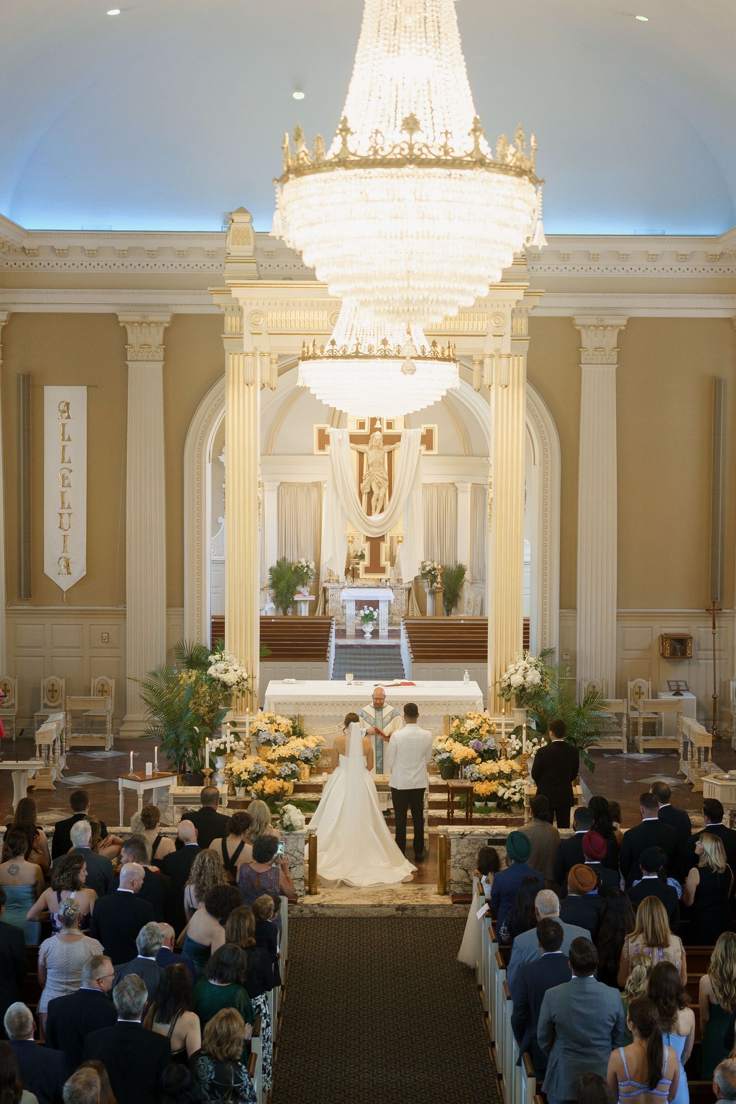 Elegant wedding ceremony in a grand ballroom with crystal chandeliers and floral arrangements.