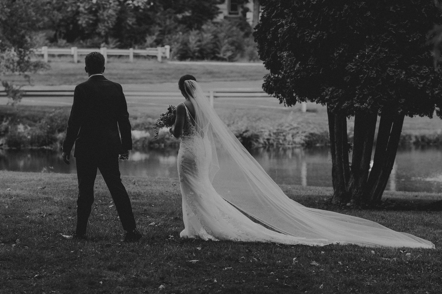 A couple walks together through a scenic outdoor setting during a wedding photoshoot in black and white.