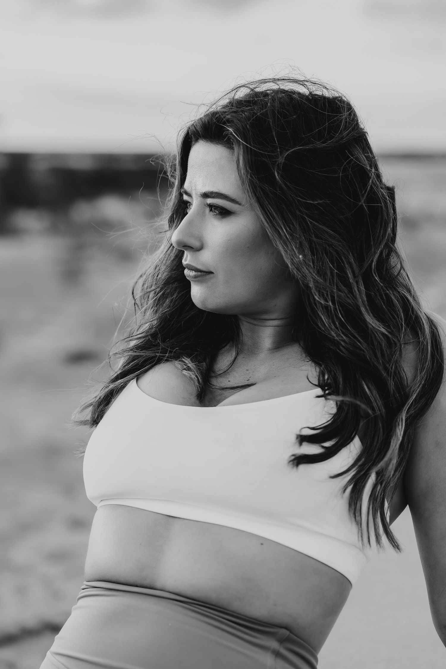 Black and white portrait of woman in athletic wear against natural backdrop.