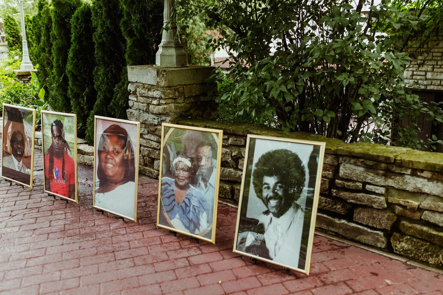 Row of vintage family photos displayed on stone wall at outdoor wedding venue.