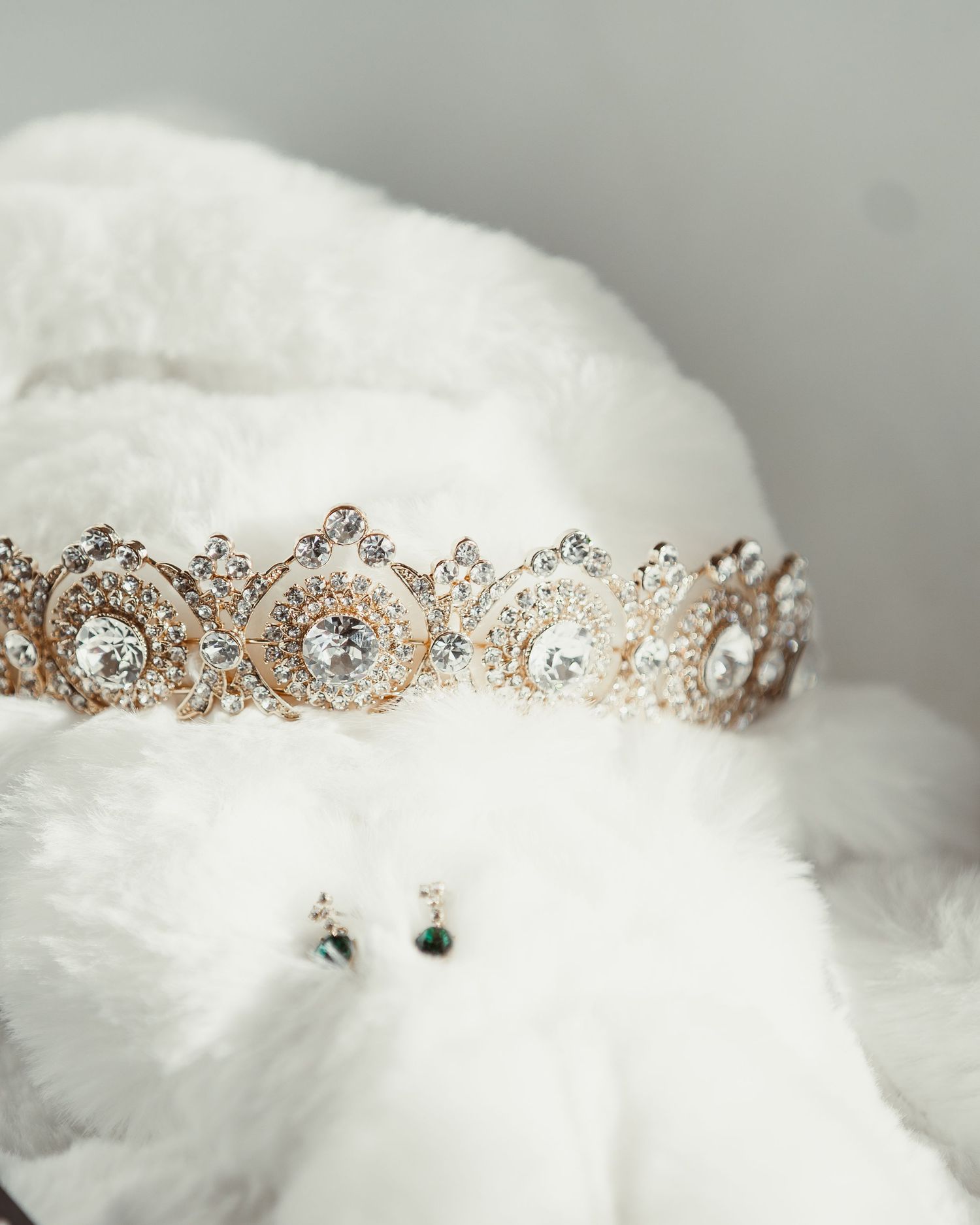 Crystal and rose gold tiara displayed on white tulle fabric.