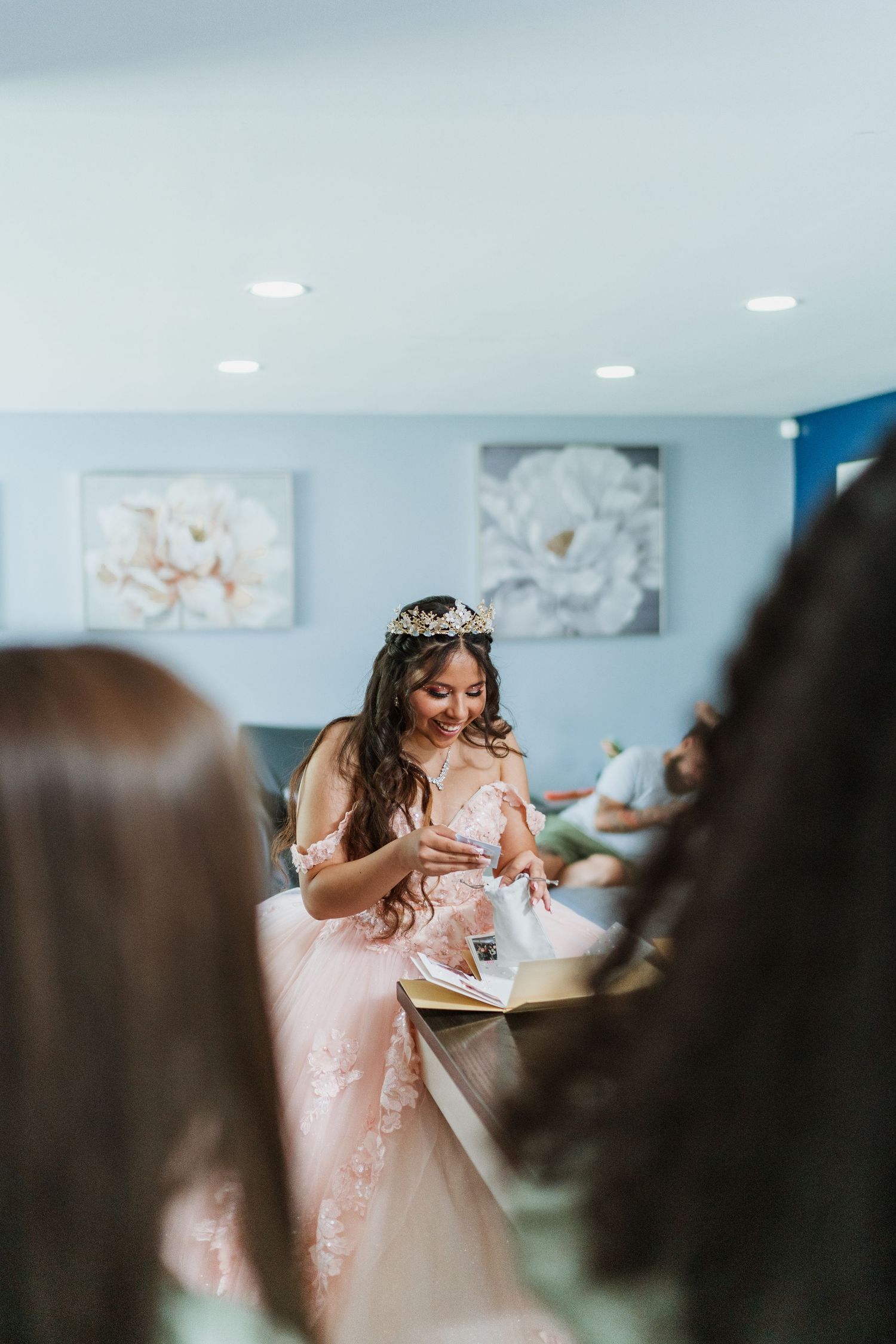 A person in a pink princess gown and tiara sits at a table during a celebration.