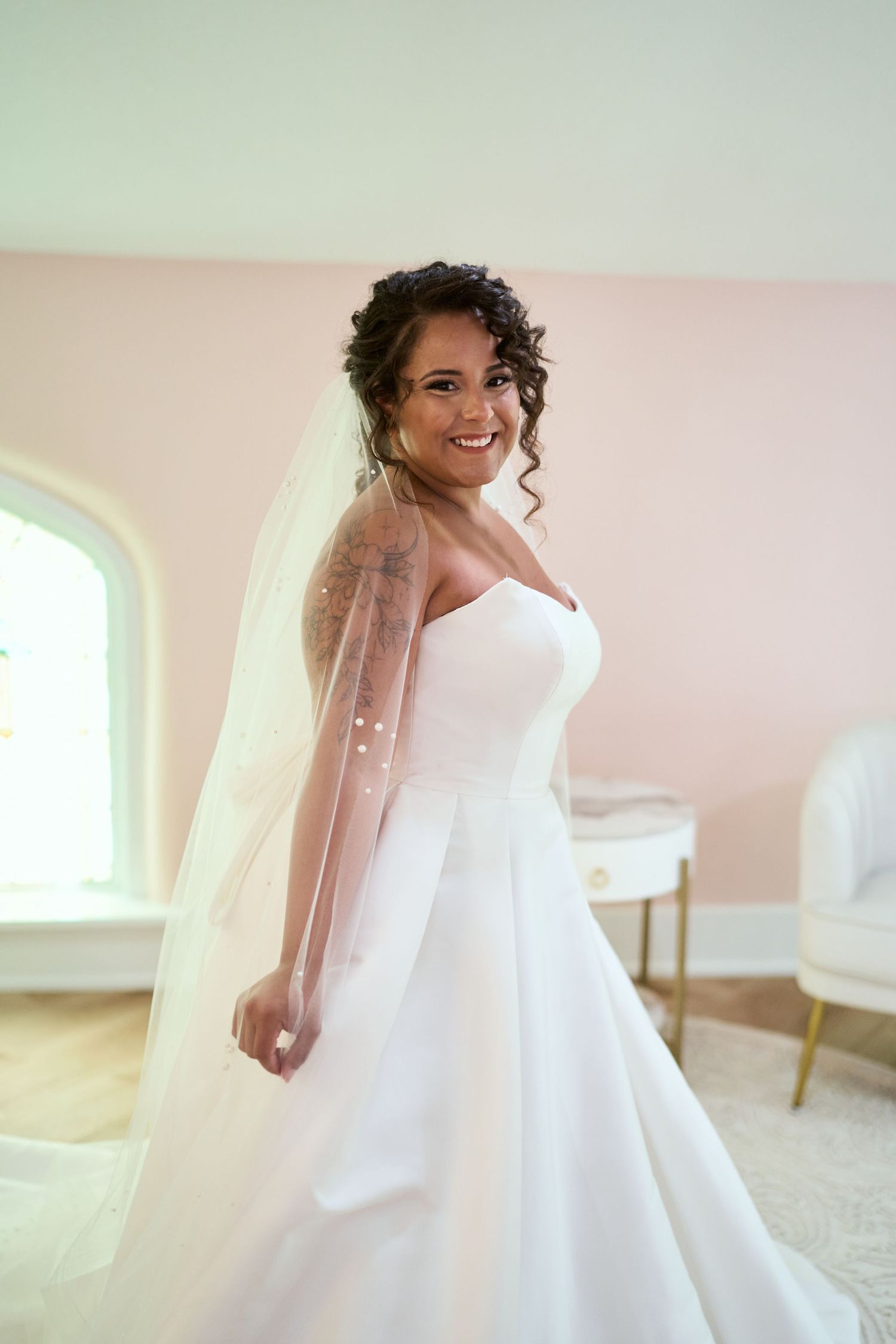 An elegant white ball gown wedding dress with dramatic silhouette in a bright room.