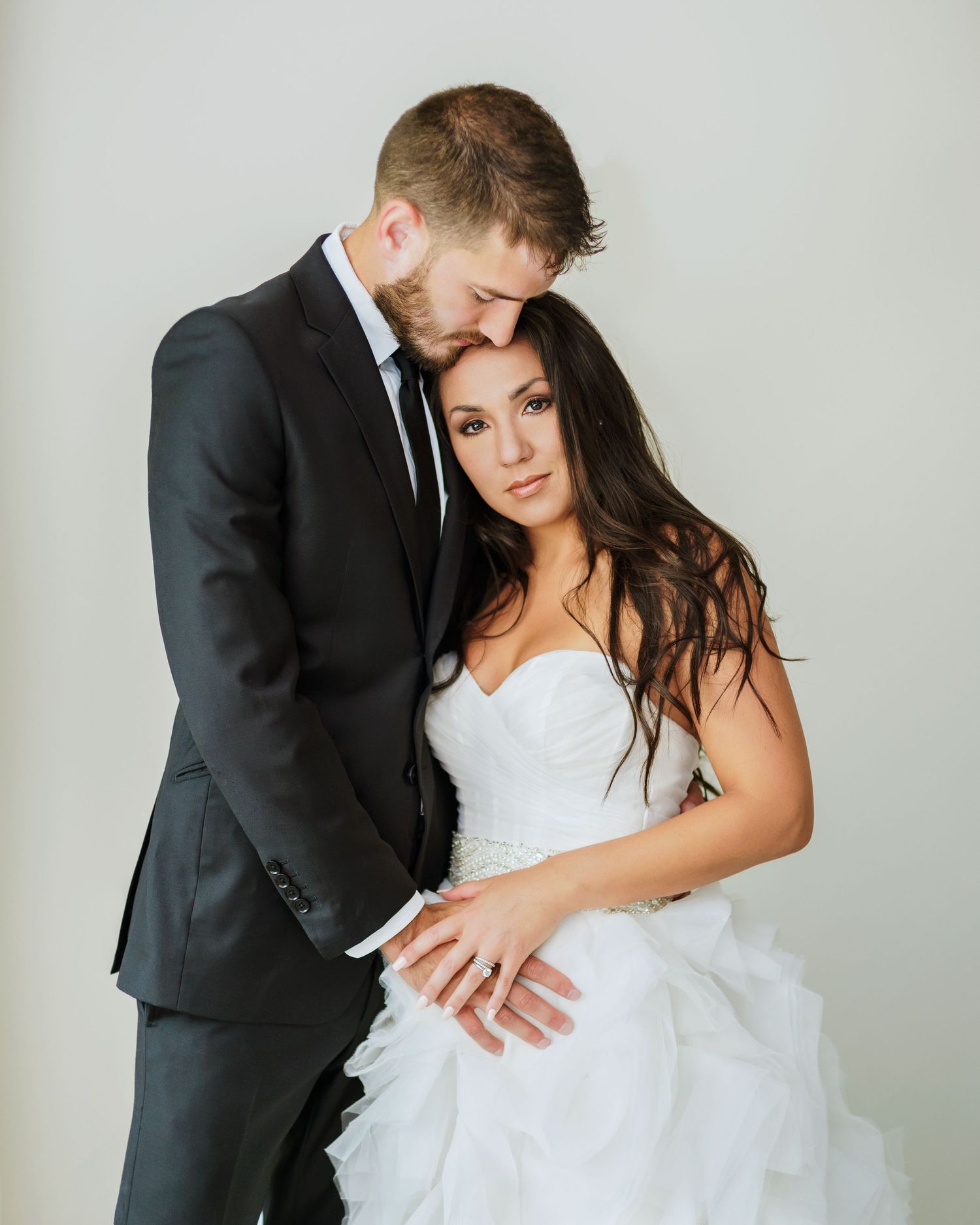 A gentle wedding portrait capturing a tender moment between newlyweds in classic black and white attire.