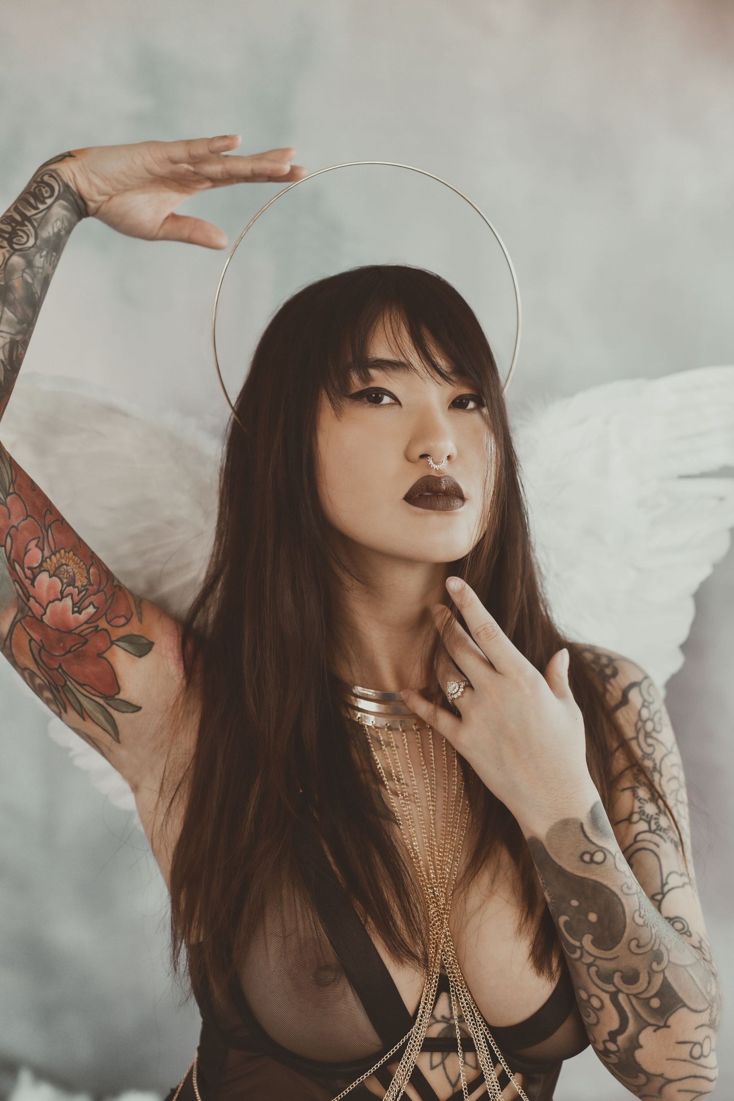Artistic portrait with halo effect and wing props in ethereal lighting.