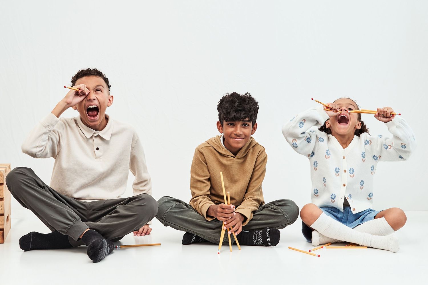 Seven images in sequence show someone sitting on floor in casual clothing making different playful poses and expressions.