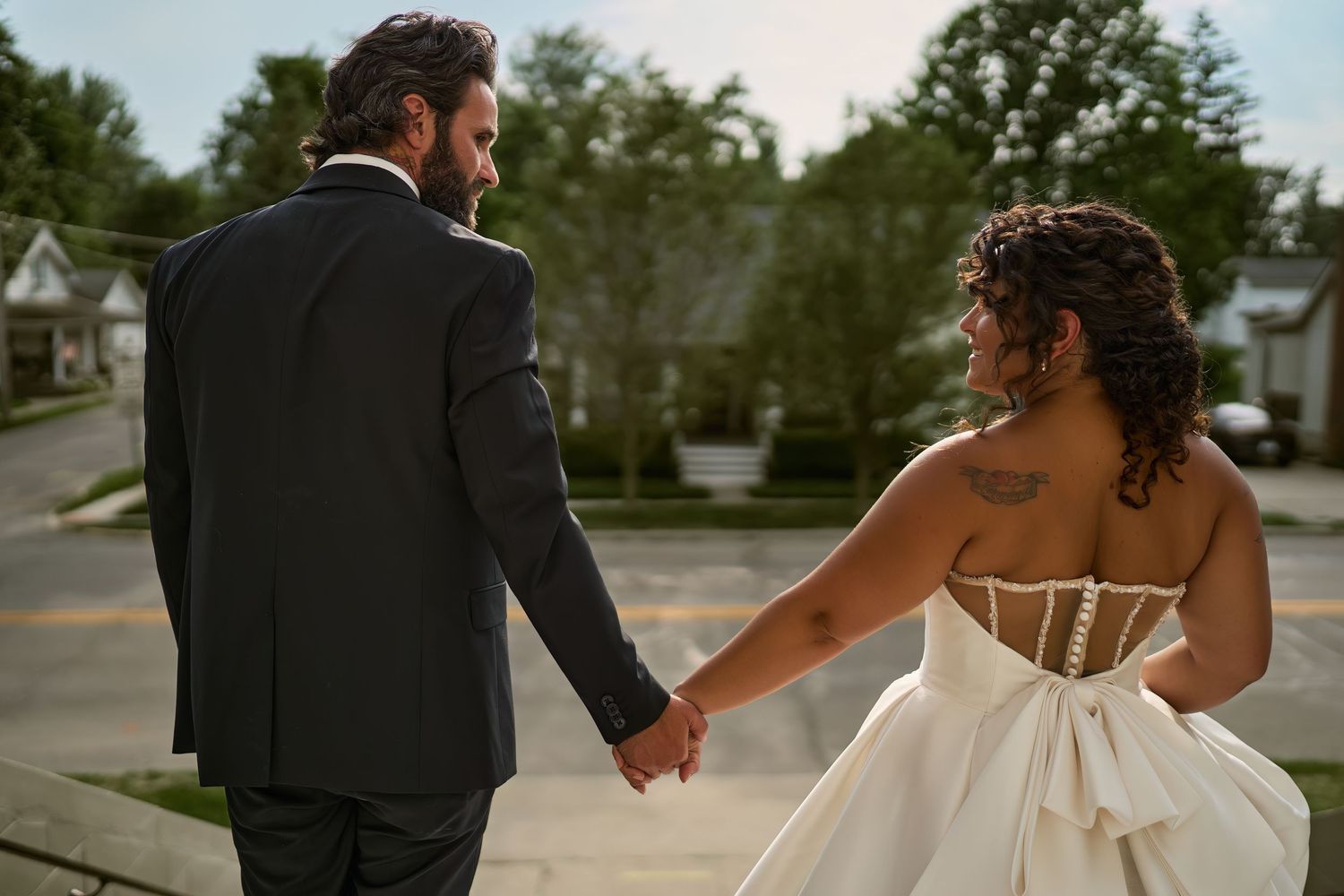 A bride and groom hold hands while walking together on their wedding day, showcasing intimate moments of love and celebration.