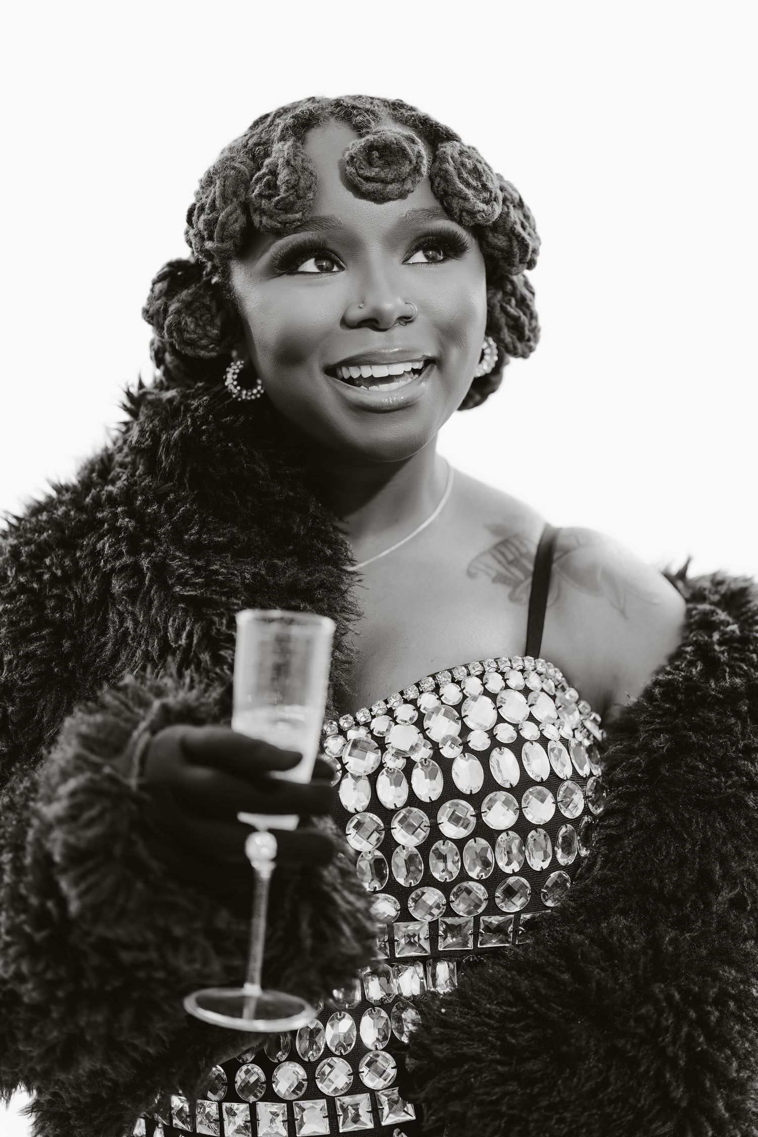 A glamorous vintage-style portrait featuring sparkling jewelry and a feather boa in black and white photography.