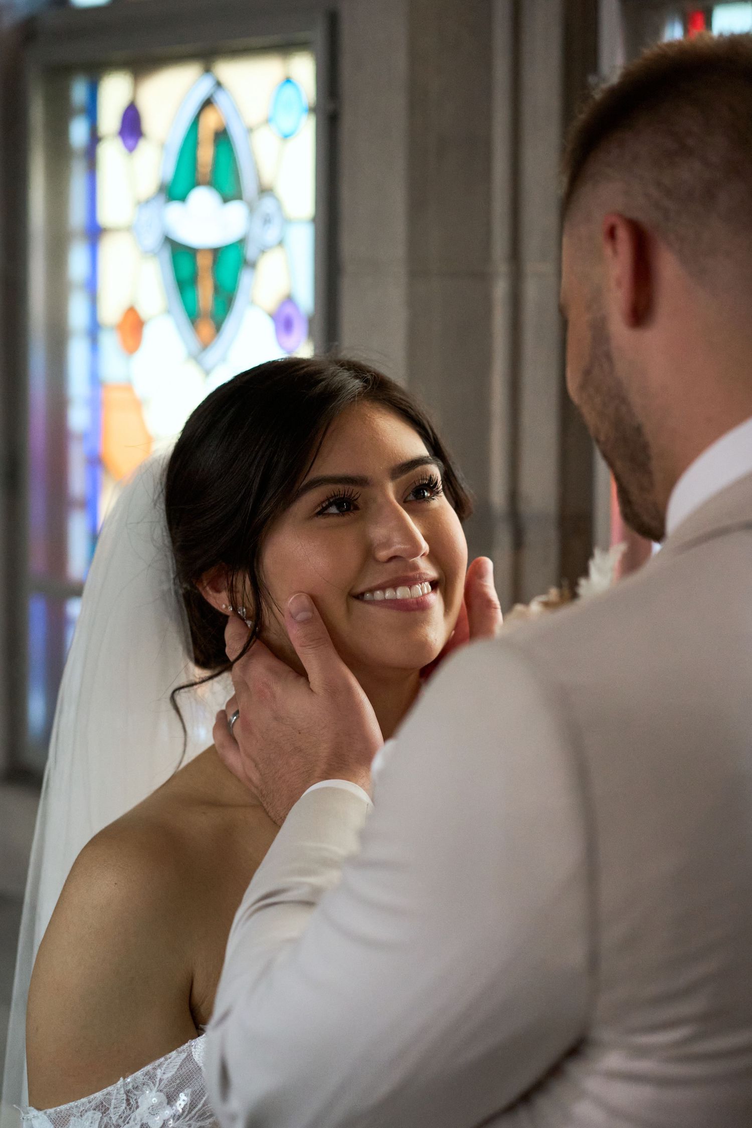 A tender moment between newlyweds captured in a sequence of photos with stained glass windows in the background.