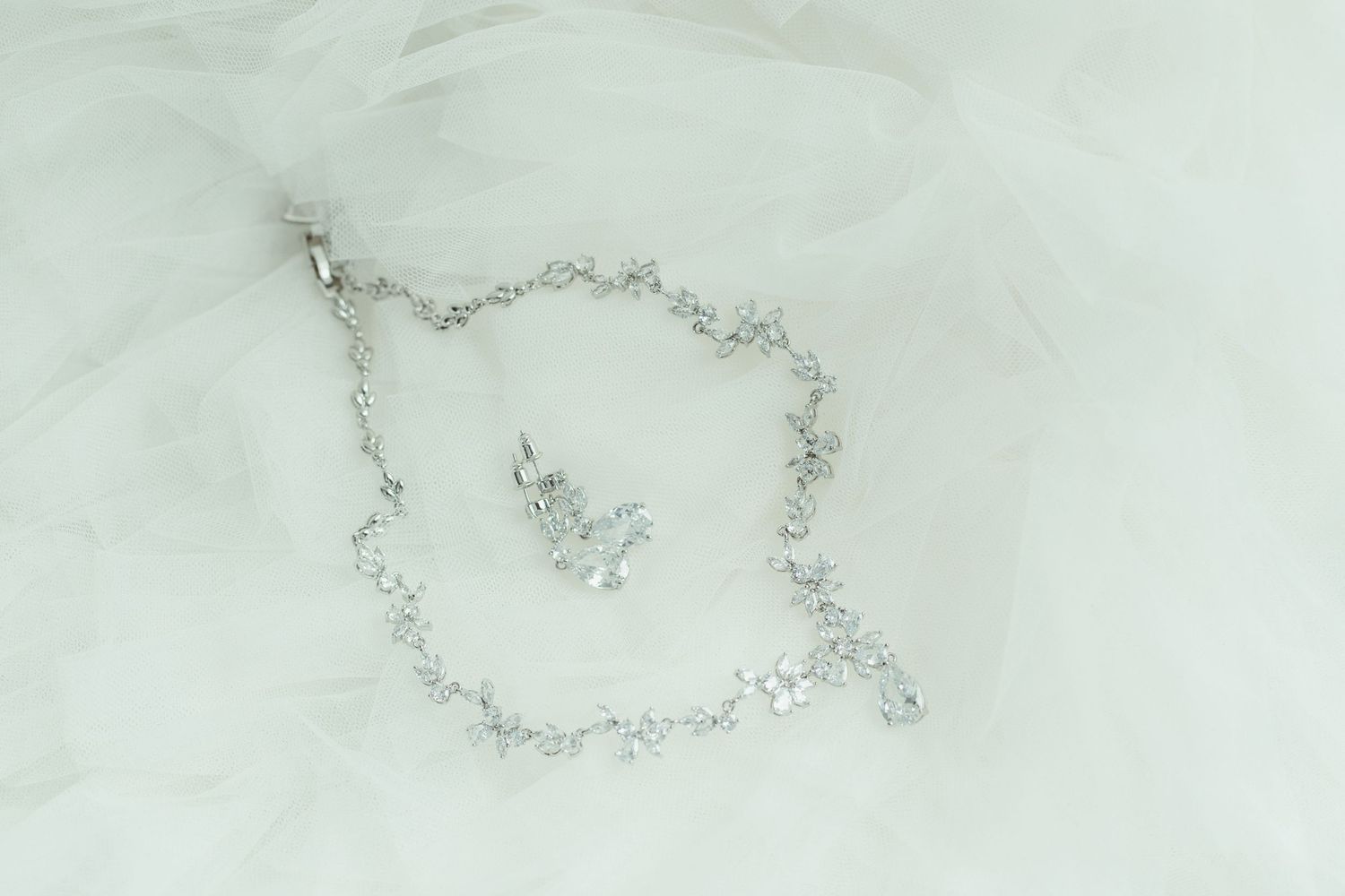 Crystal bridal necklace arranged in an ornate pattern against white textured background.