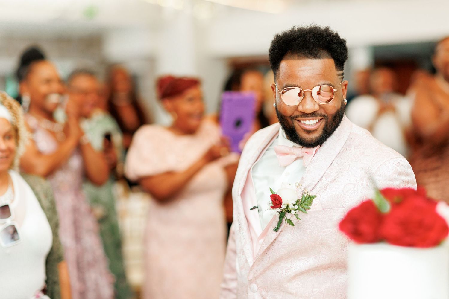 A joyful celebration moment at an indoor wedding reception with pink and white decor.