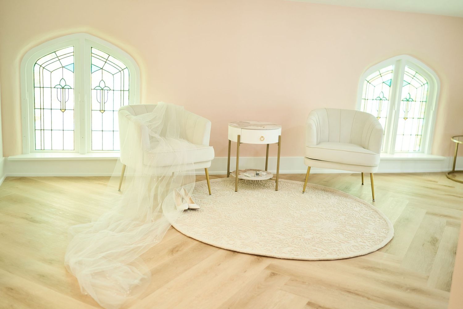 Bright minimalist wedding room interior with white chairs, round table and gothic windows with light wood flooring.