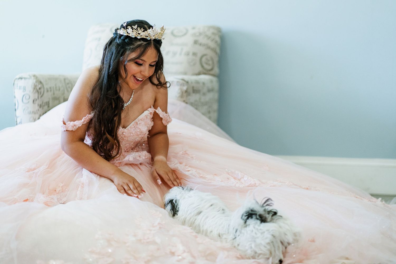 Elegant quinceañera photoshoot featuring a flowing pink ball gown in a light-filled room.