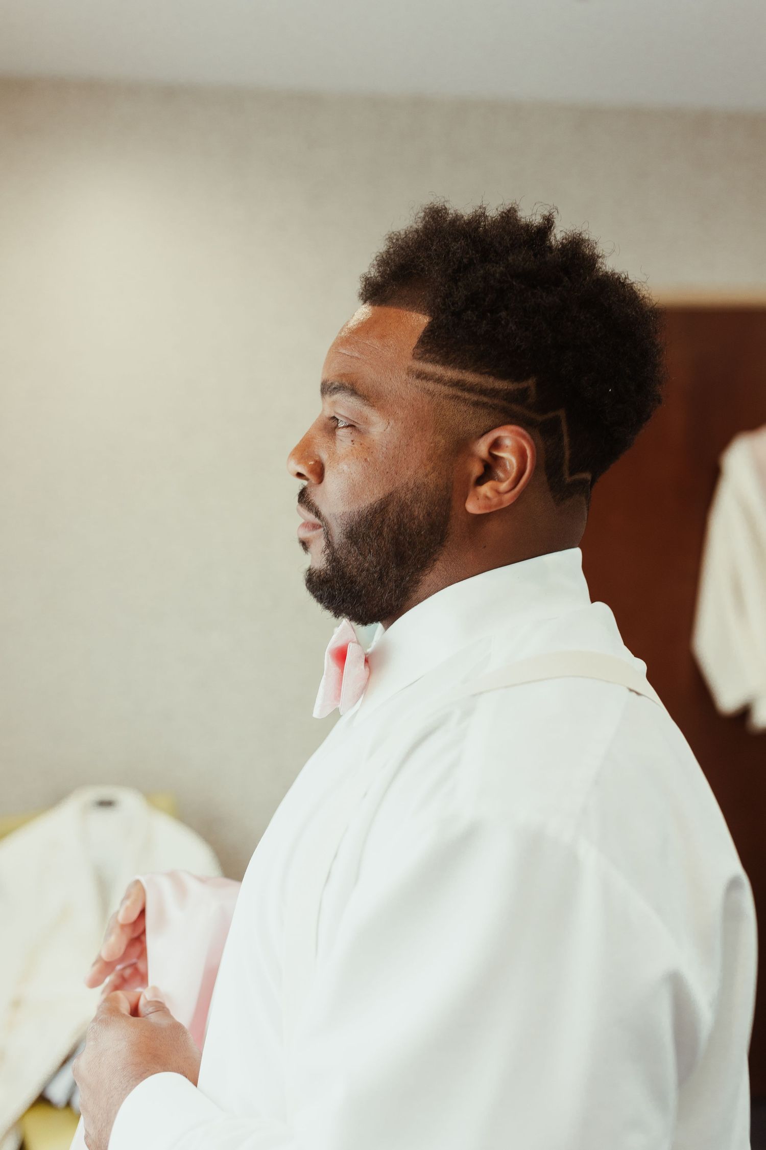 Side profile of person in white formal attire against neutral background.