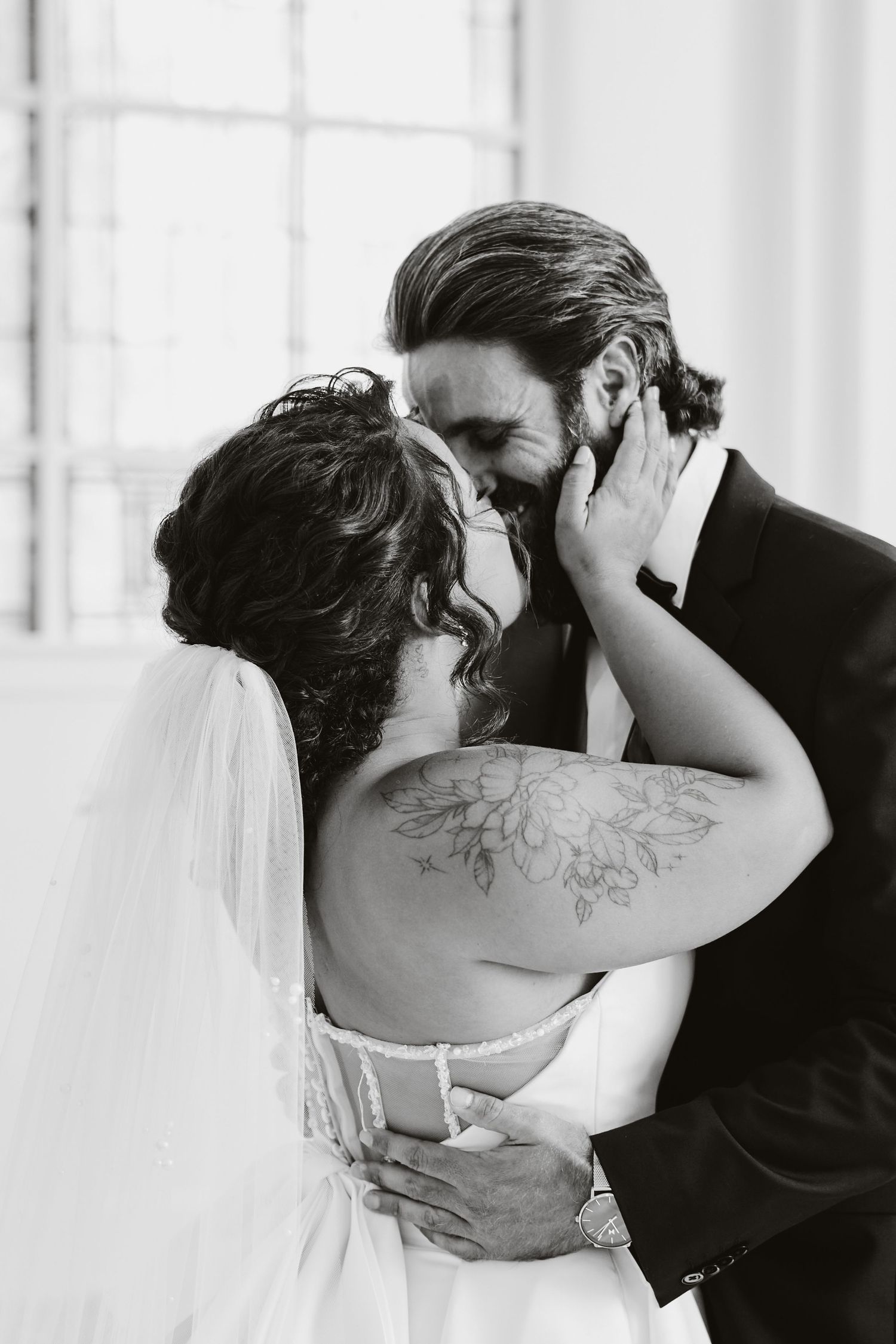 Black and white portrait of a tender moment between newlyweds sharing an intimate embrace.