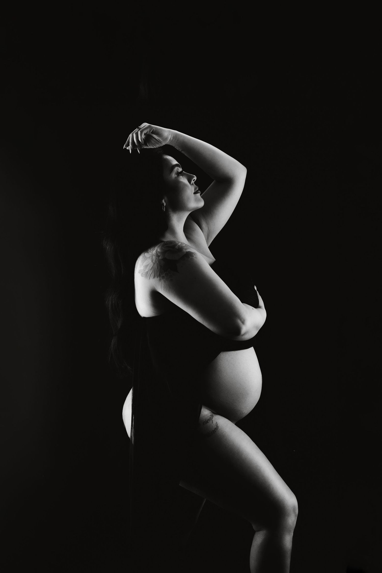 A series of artistic black and white maternity photos showing silhouettes of a pregnant figure in different poses.