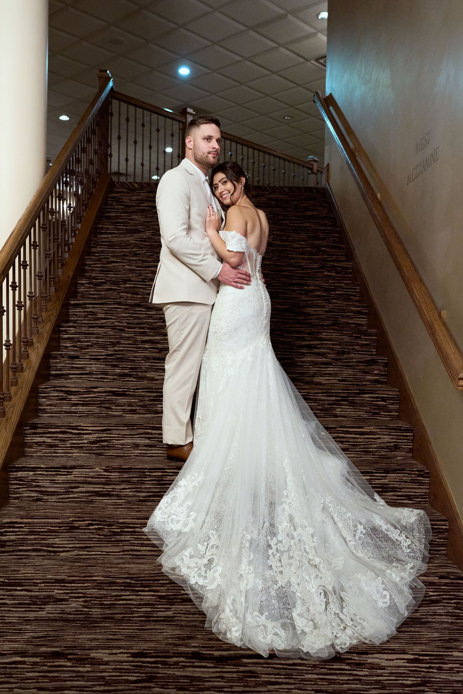 A romantic wedding couple embraces on a staircase with stone walls and wooden railings in a series of photos.