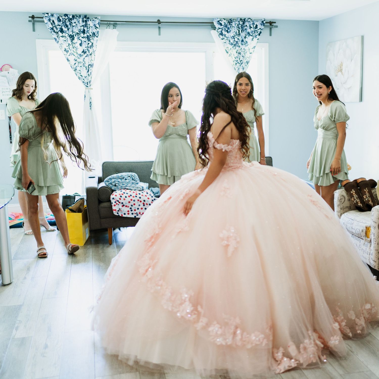 A flowing pink ball gown with delicate lace details photographed in a bright white room.