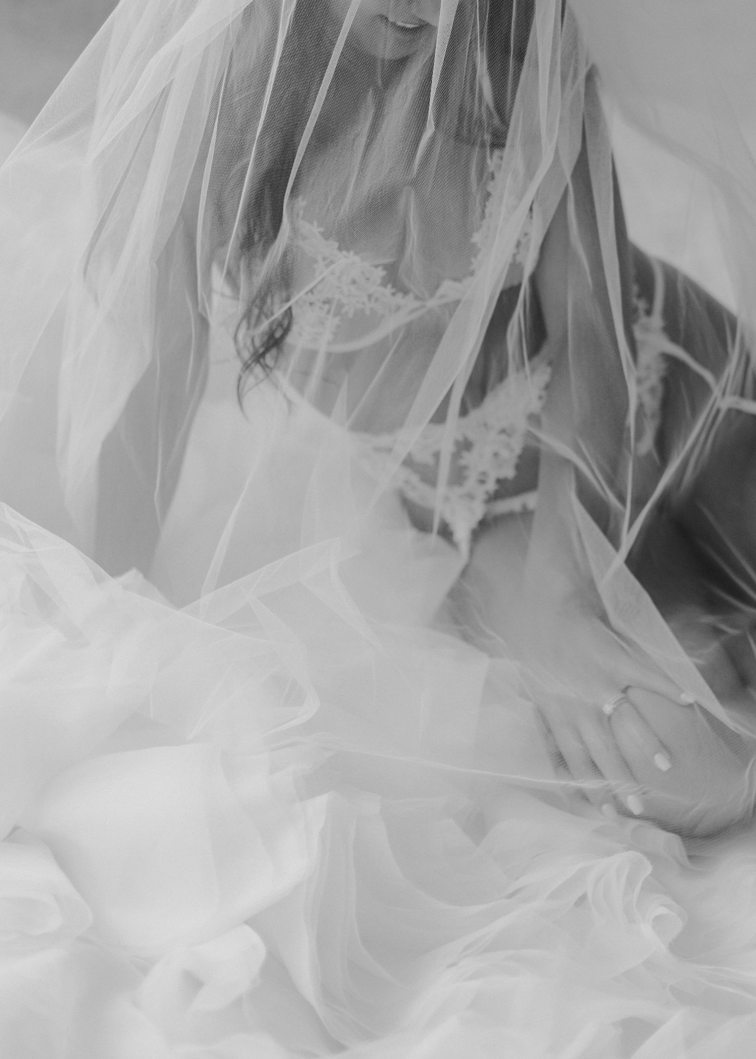 Ethereal black and white photo of flowing bridal veil and lace details.