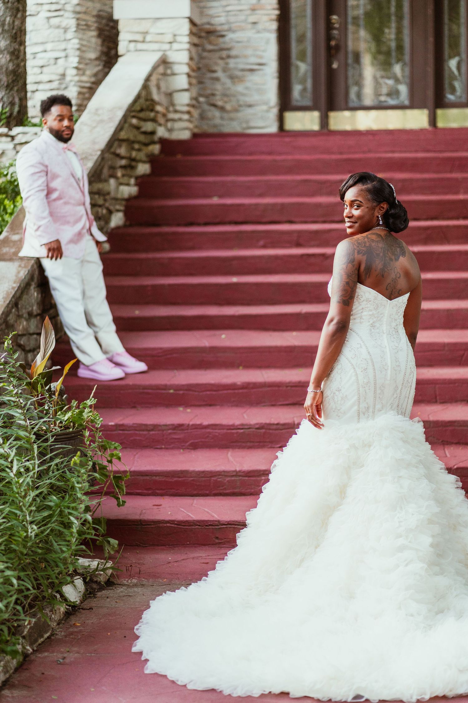 A candid wedding moment captured on red stairs showing a beautiful gown.